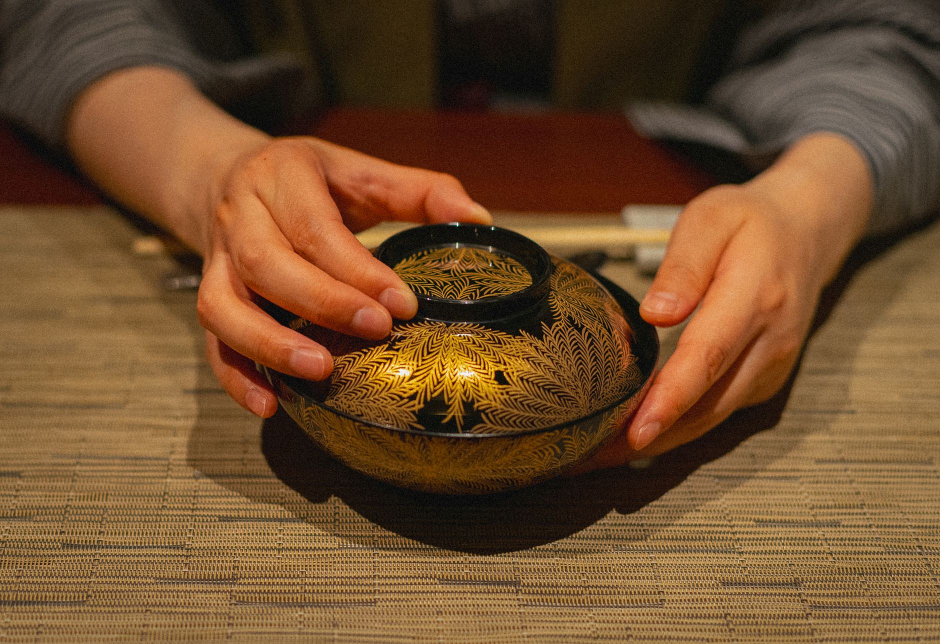 Ancient Japanese lacquerware bowl with gold maki-e decoration showing autumn maple leaves on glossy black urushi surface from Edo period.