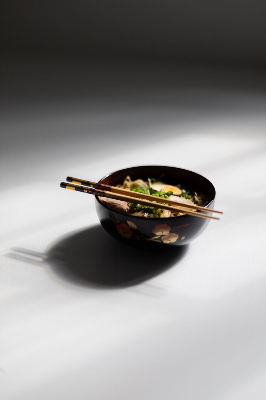 Ancient Japanese lacquerware bowl with gold maki-e decoration showing autumn maple leaves on glossy black urushi surface from Edo period.