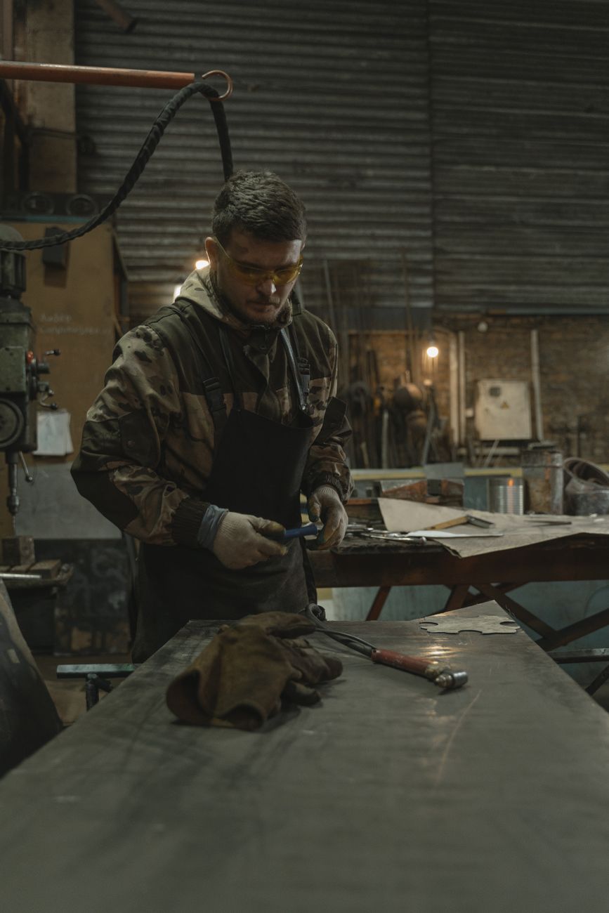 Blacksmith hammering red-hot steel on anvil in traditional Japanese knife forge with charcoal fire glowing.