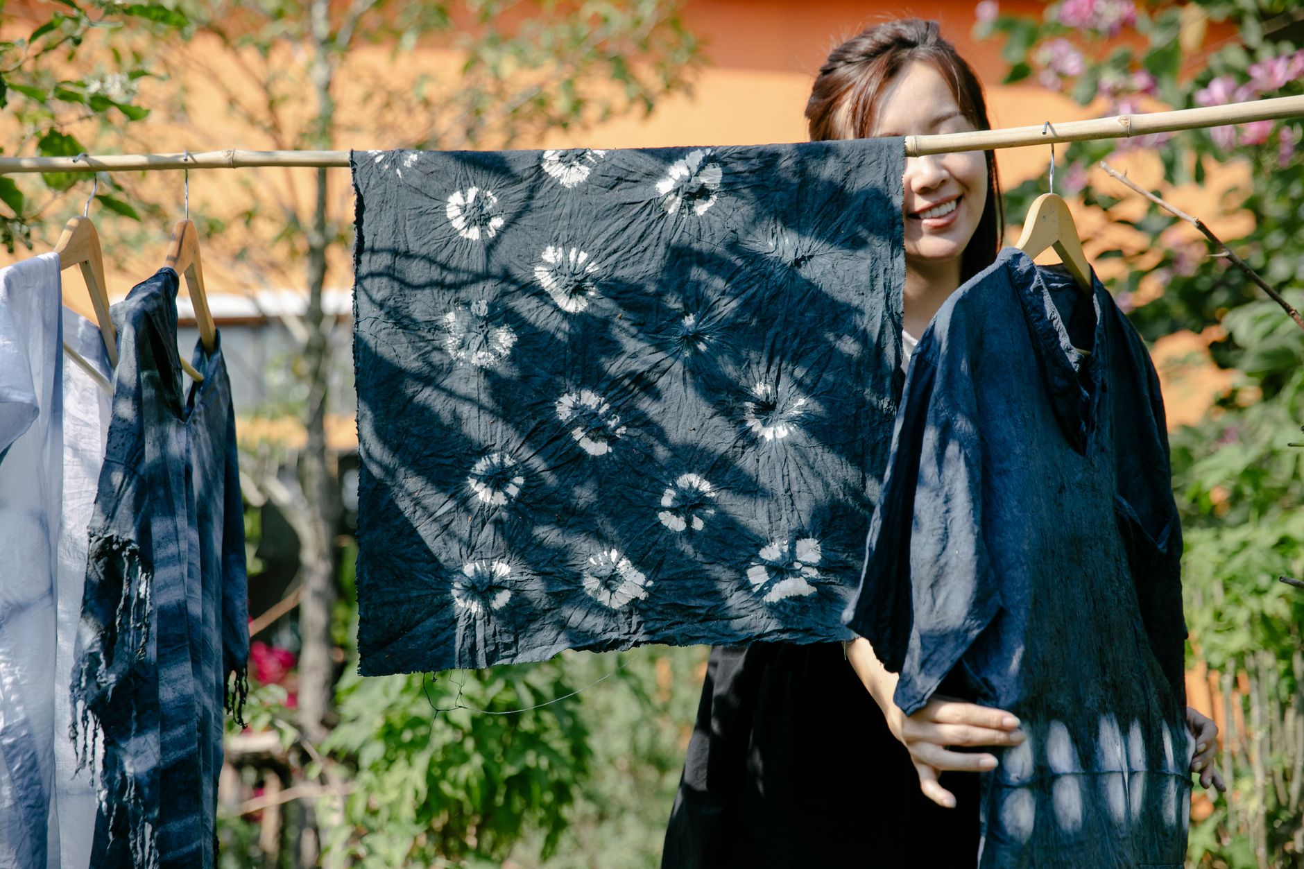 Artisan applying rice paste resist through metal cone onto white silk kimono fabric stretched on wooden frame for yuzen dyeing process.