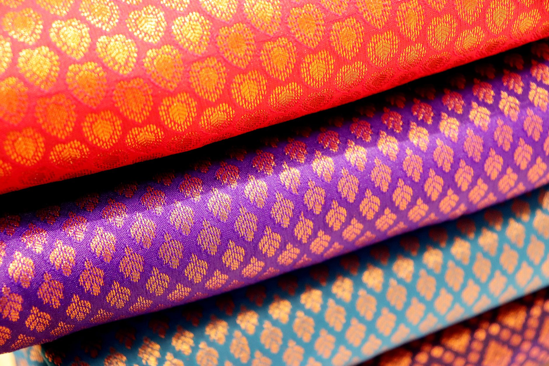 Artisan threading multicolored silk yarns through a traditional jacquard loom in a Kyoto Nishijin weaving workshop.