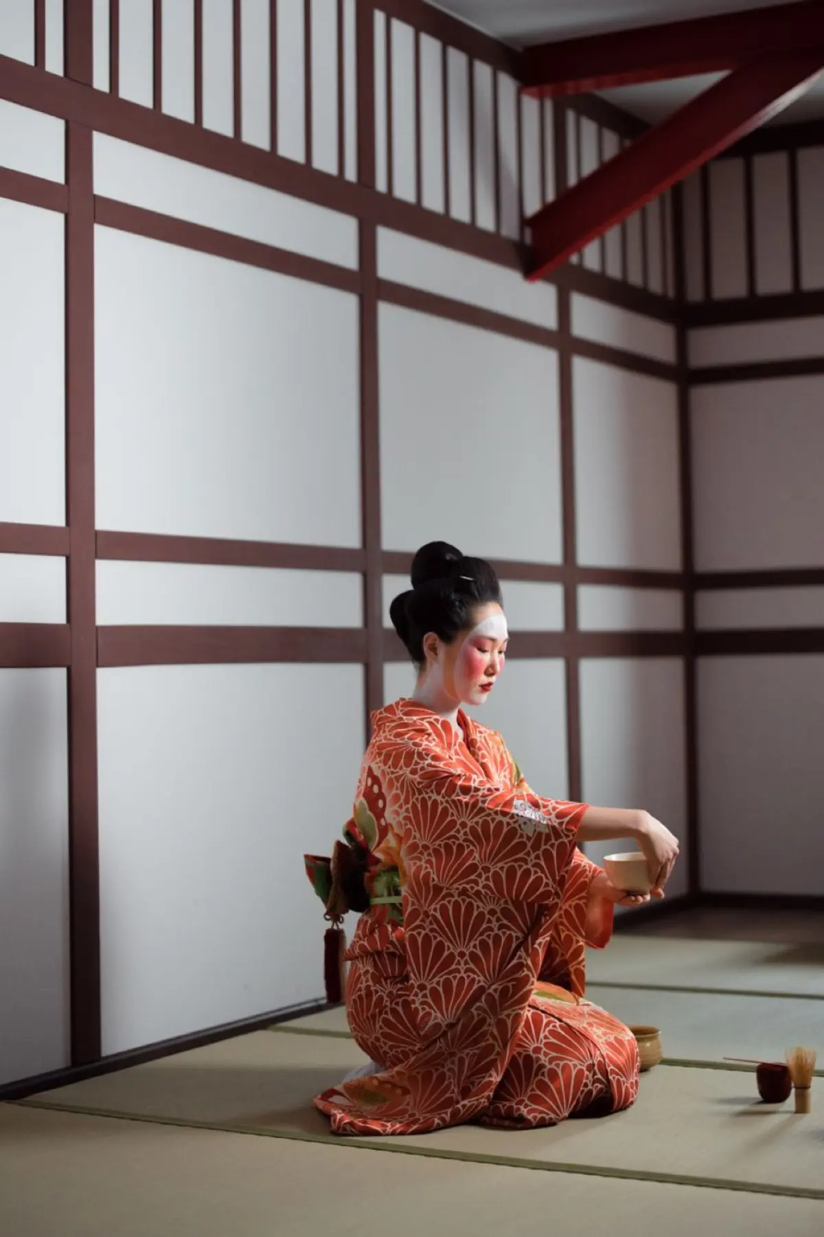 Traditional Japanese tea room showing low ceiling with exposed wooden beams, tatami flooring, tokonoma alcove, and small square window casting natural light.