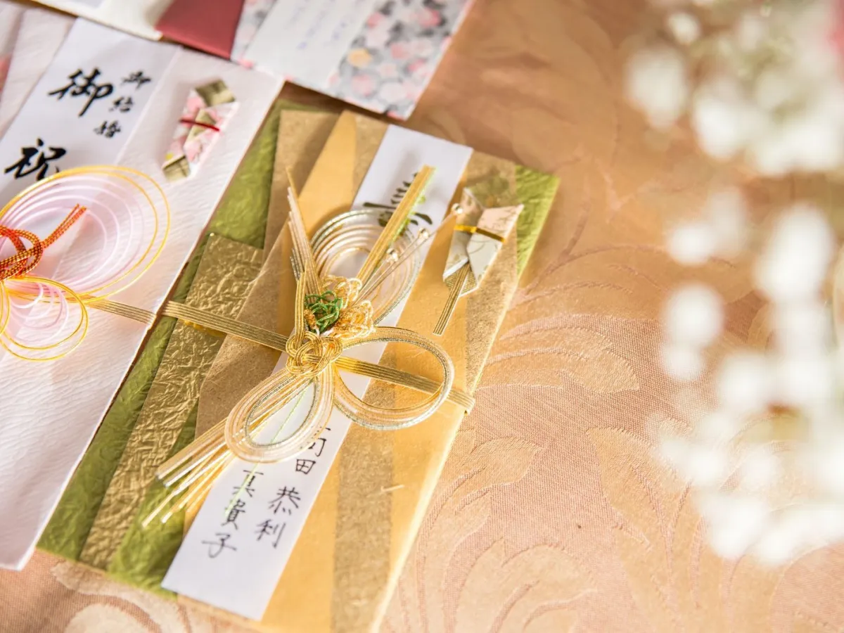 A formal Japanese gift wrapped in white paper with a red-and-white mizuhiki cord and noshi attachment