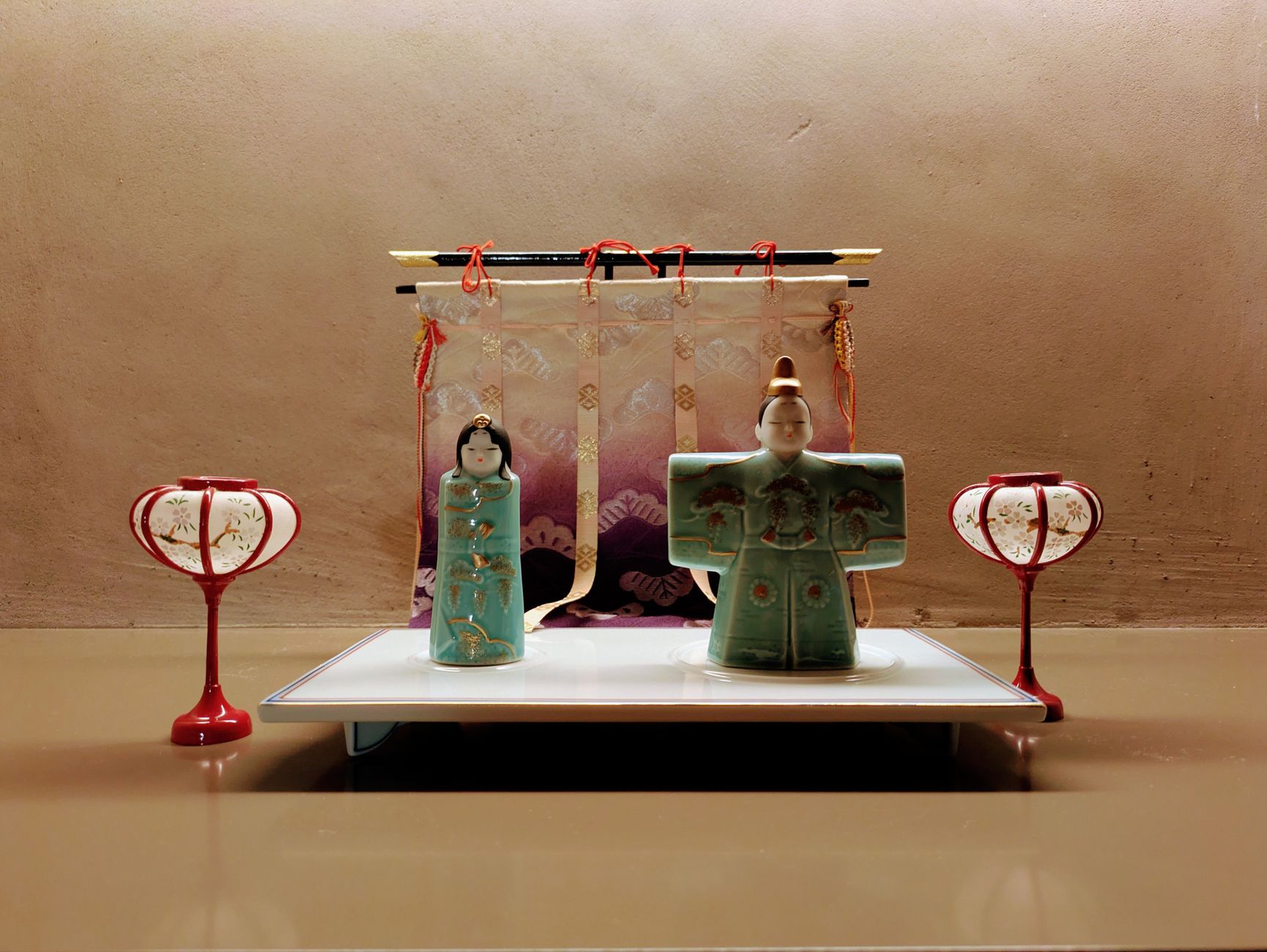 Two hands presenting a wrapped gift with both palms in traditional Japanese manner, cloth furoshiki wrapping visible.