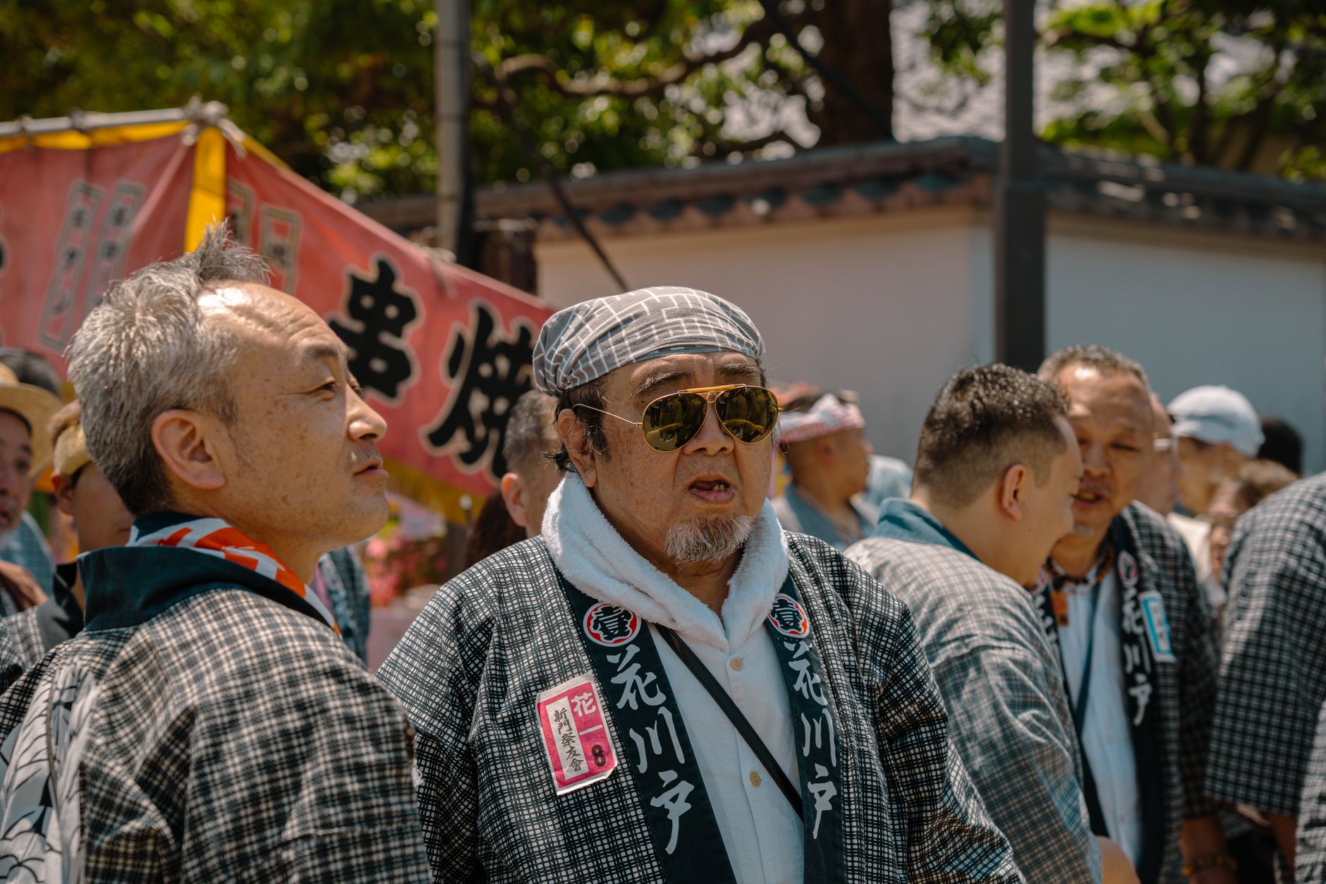 Two Japanese businesspeople in formal attire bowing to each other at different angles on a city street in Tokyo.