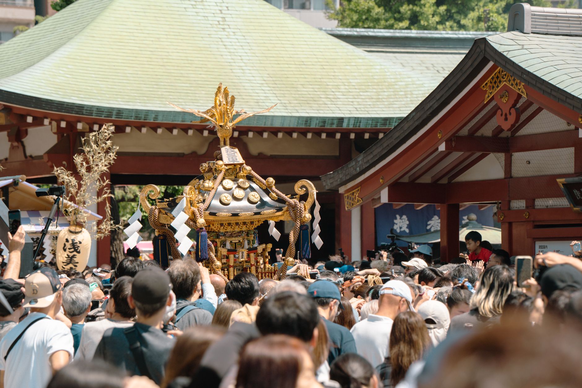 Visitor rinses hands with wooden ladle at stone water basin outside Japanese Shinto shrine entrance.