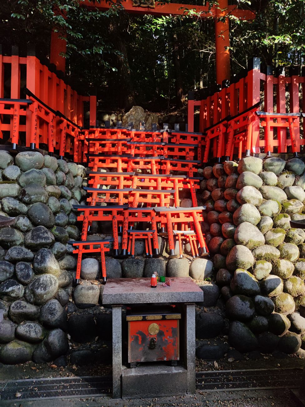 Visitor rinses hands with wooden ladle at stone water basin outside Japanese Shinto shrine entrance.