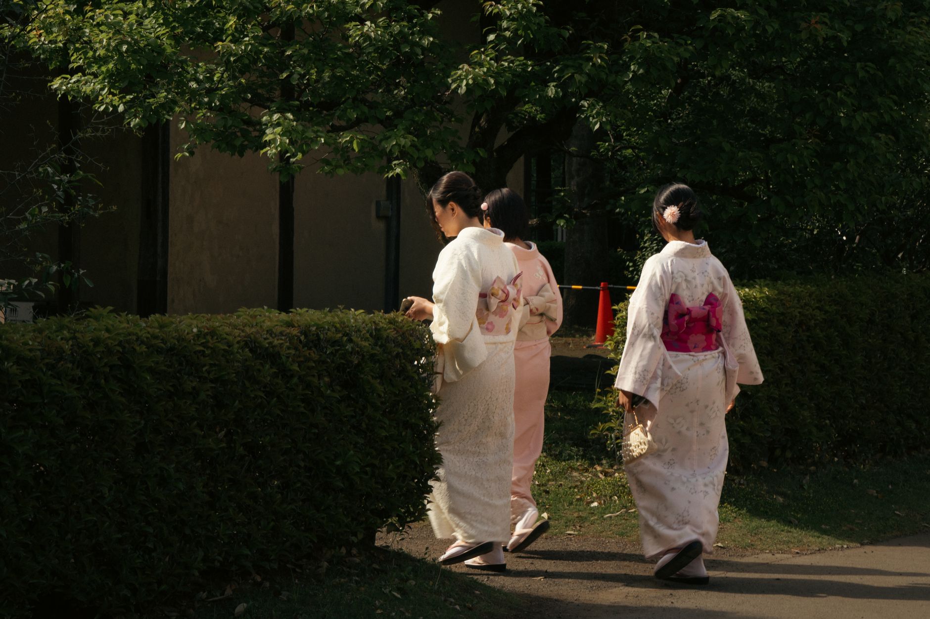 Guests in yukata robes walking along a traditional wooden corridor toward an outdoor onsen bath at sunset.