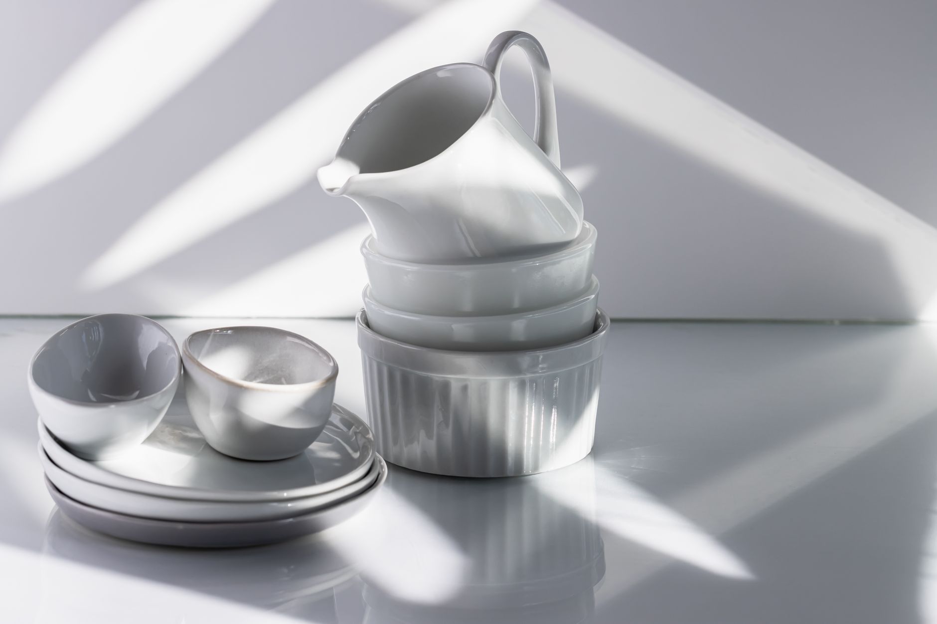 White and blue porcelain bowls and plates with minimalist designs stacked together, showcasing traditional Hasami ware pottery from Nagasaki, Japan.