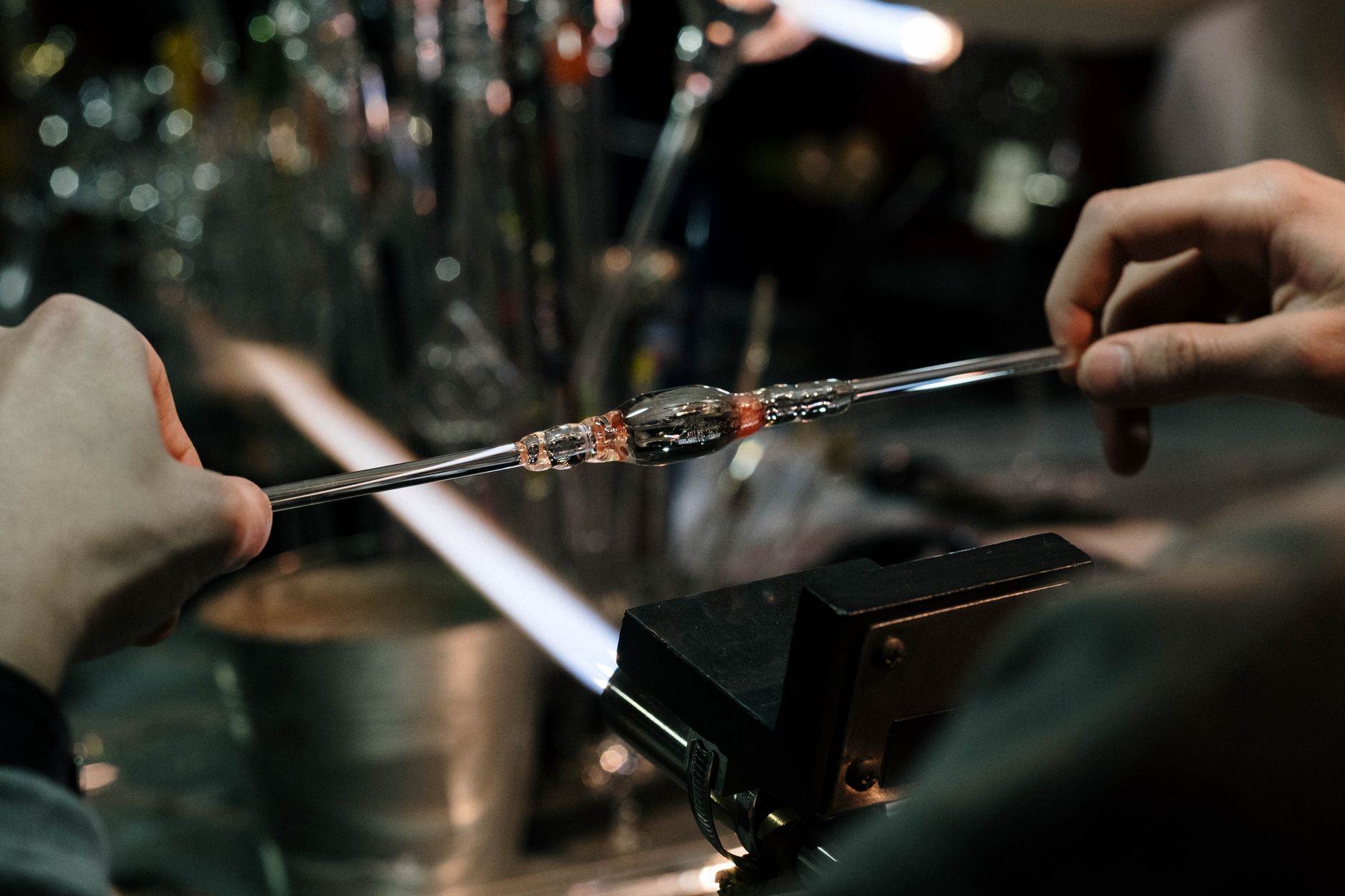 Artisan gathering molten Tsugaru Bidoro glass on a blowpipe from a furnace glowing with intense orange heat.