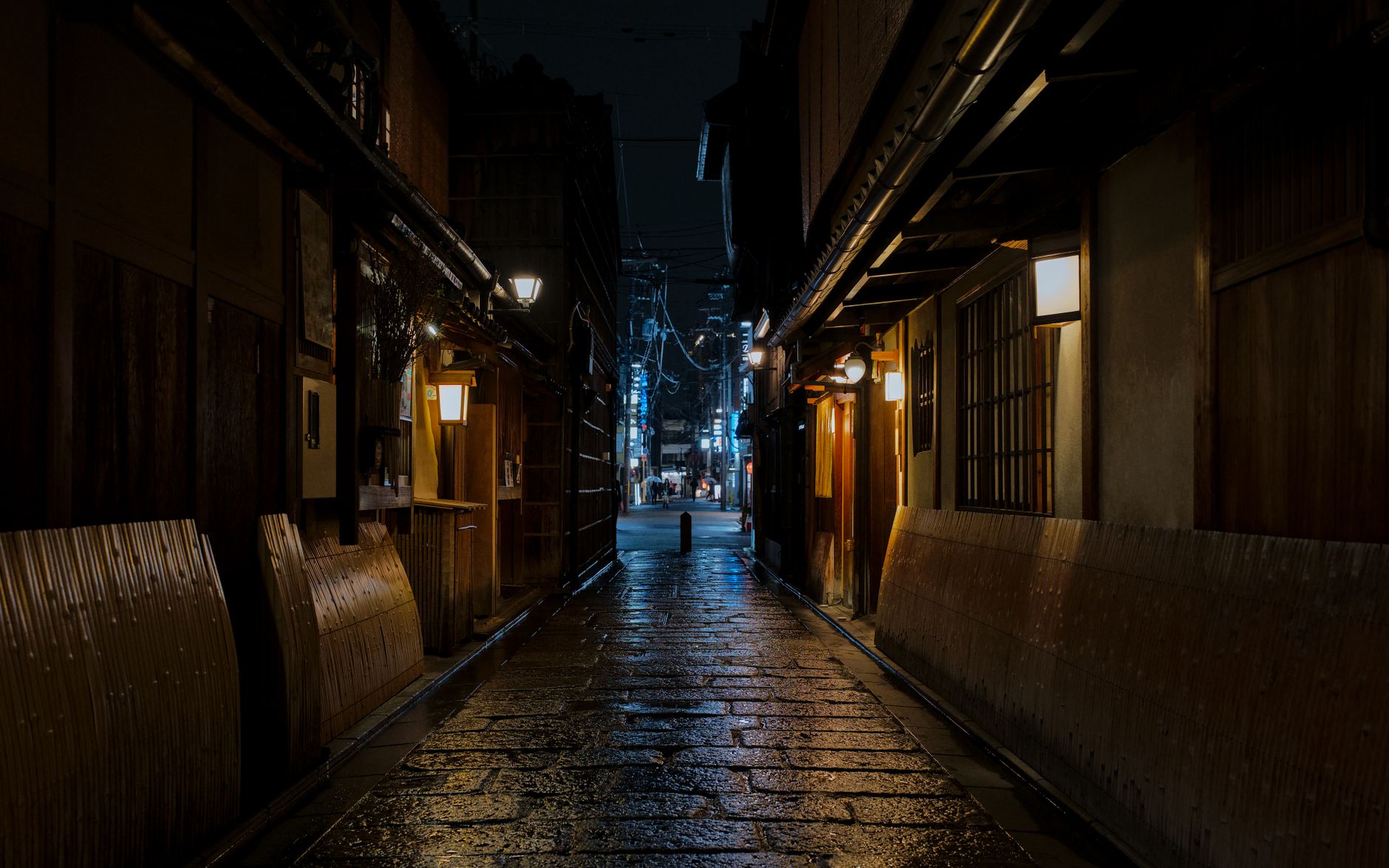 Wooden entrance of a traditional ochaya tea house in Kyoto's Gion district with bamboo lattice screens and stone pathway.