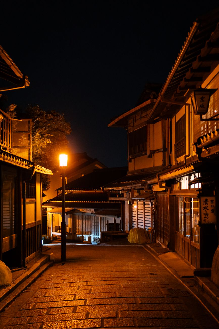 Wooden entrance of a traditional ochaya tea house in Kyoto's Gion district with bamboo lattice screens and stone pathway.
