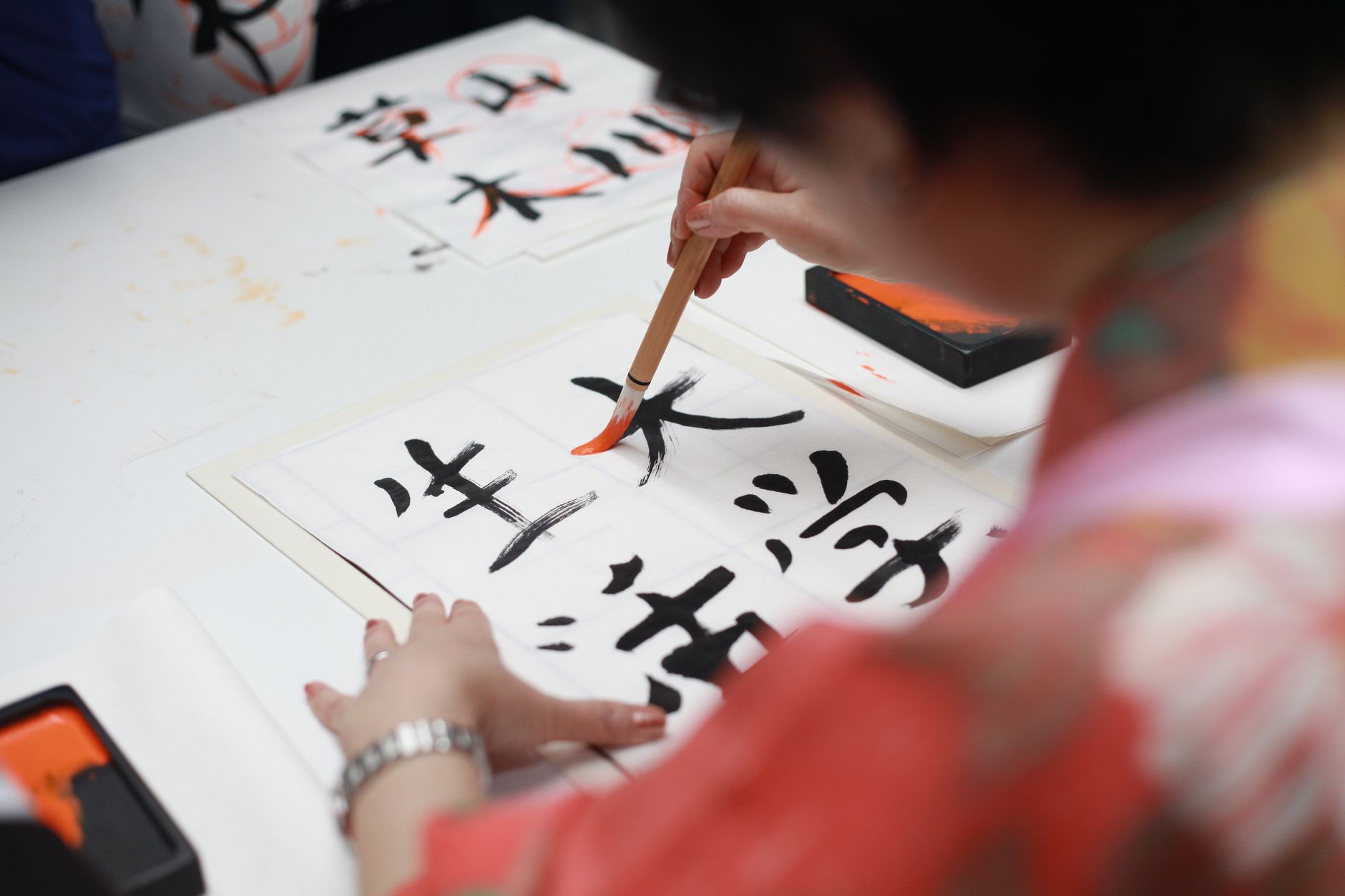 Hanging scroll with bold black calligraphy characters displayed in traditional tea room alcove beside bamboo flower arrangement.