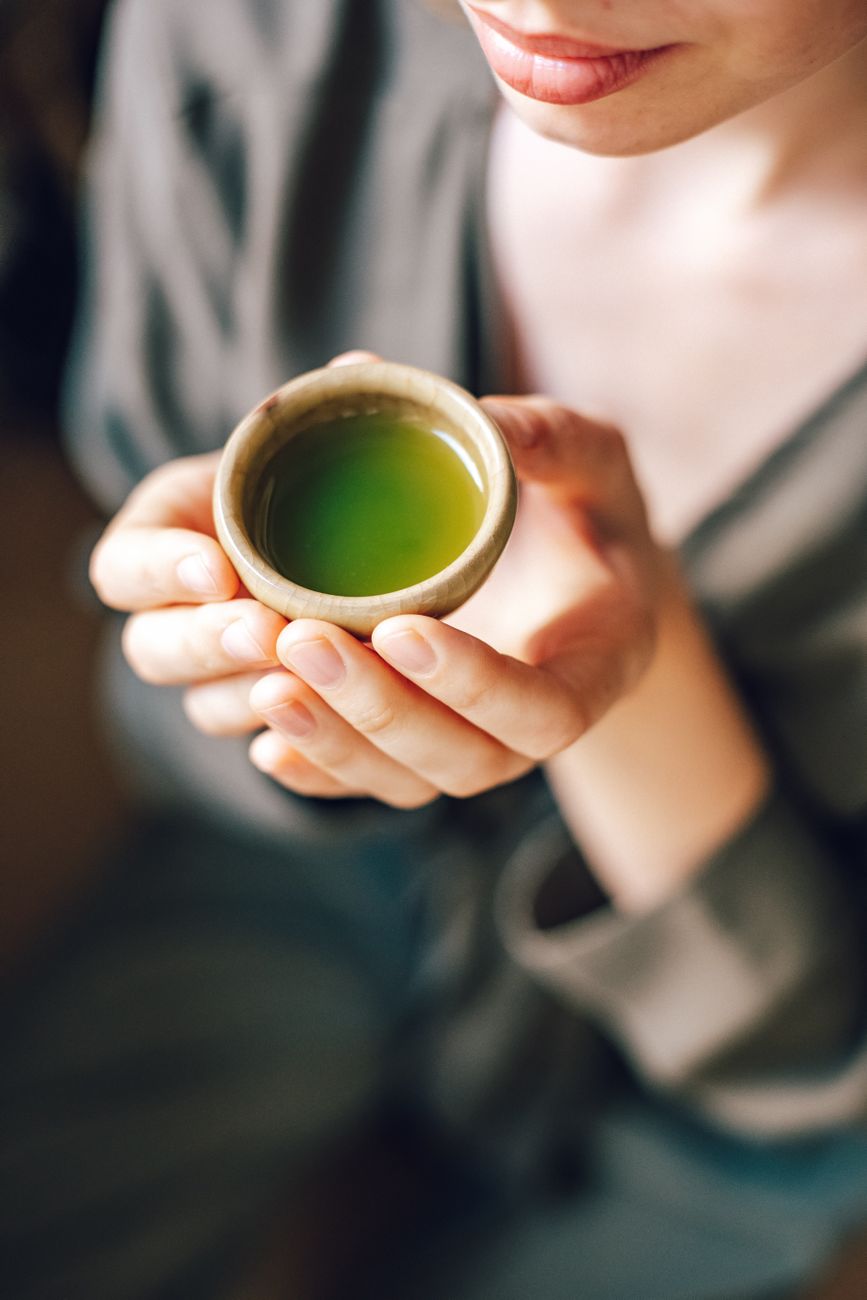 A tea practitioner whisking matcha in a ceramic bowl during a traditional Japanese tea ceremony in a quiet tatami room.