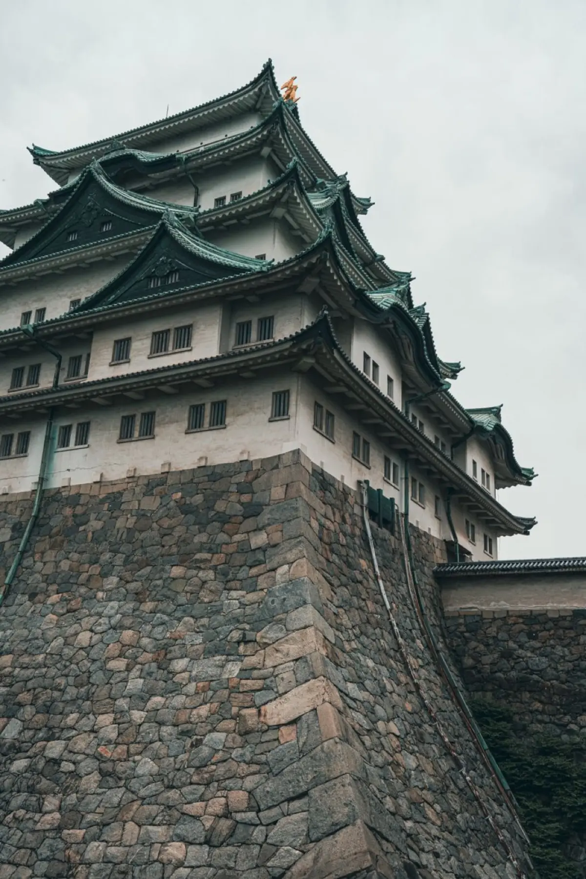 A white Japanese castle keep with curved gables rising above massive sloping stone walls