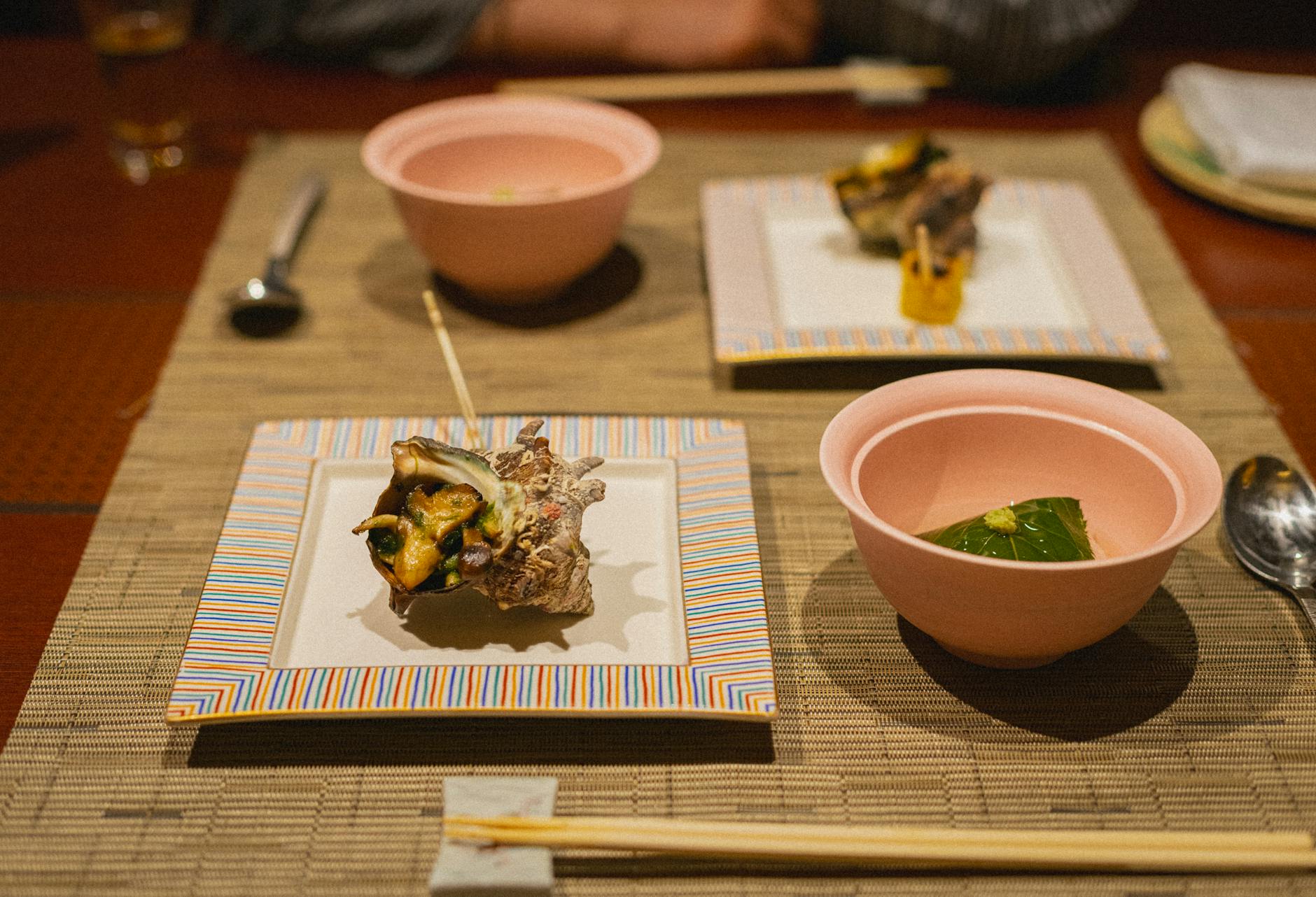 Traditional Japanese meal arranged on a wooden tray with rice, miso soup, grilled fish, pickles, and vegetables in separate small bowls.
