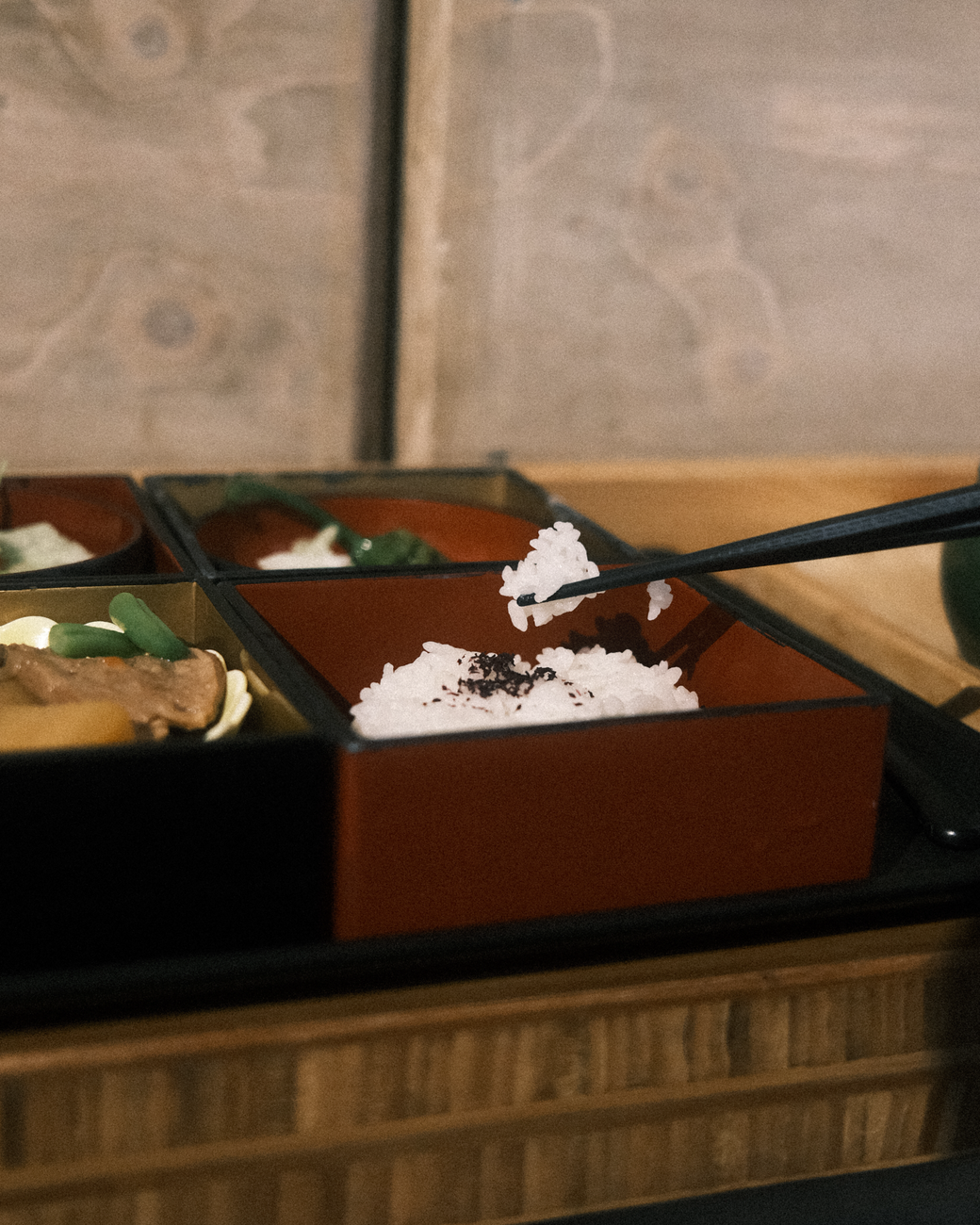 Traditional Japanese meal arranged on a wooden tray with rice, miso soup, grilled fish, pickles, and vegetables in separate small bowls.