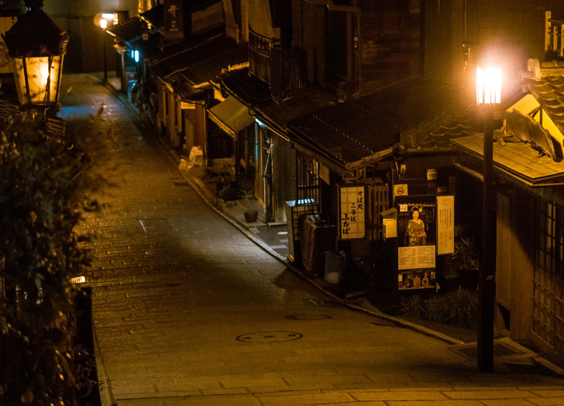 Traditional Kyoto machiya townhouse showing distinctive narrow street-facing facade with wooden lattice windows and deep interior extending backward.