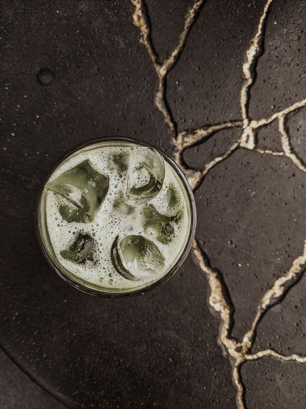 Traditional granite millstone grinding vibrant green tea leaves into fine matcha powder in a Japanese tea production facility.