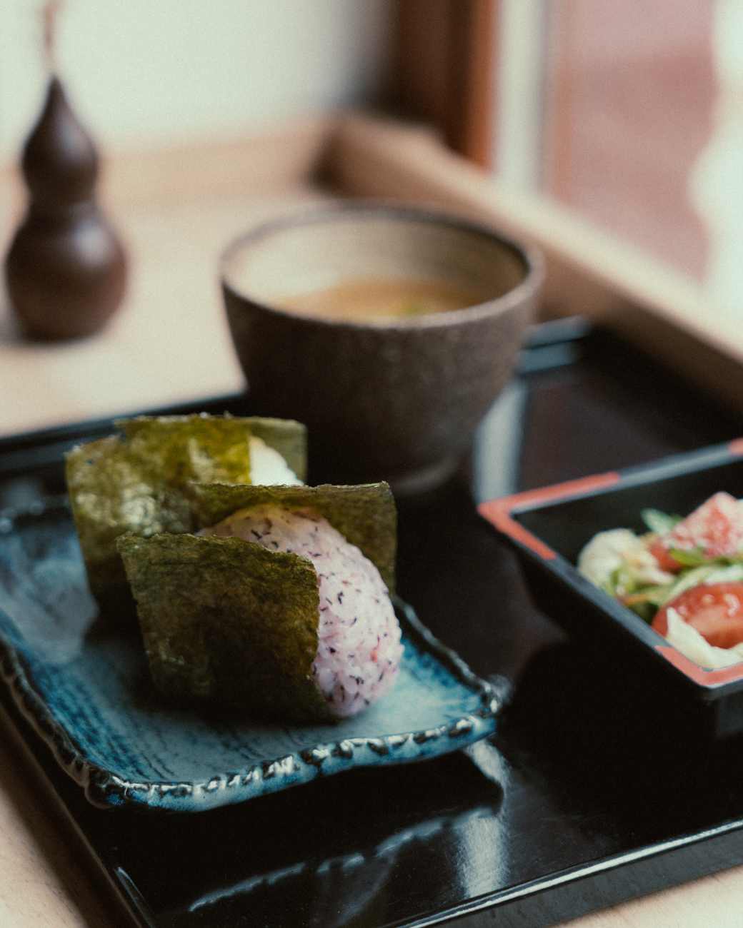 Traditional Japanese meal arrangement showing miso soup, rice bowl, grilled fish, pickled vegetables, and simmered dish on individual plates.