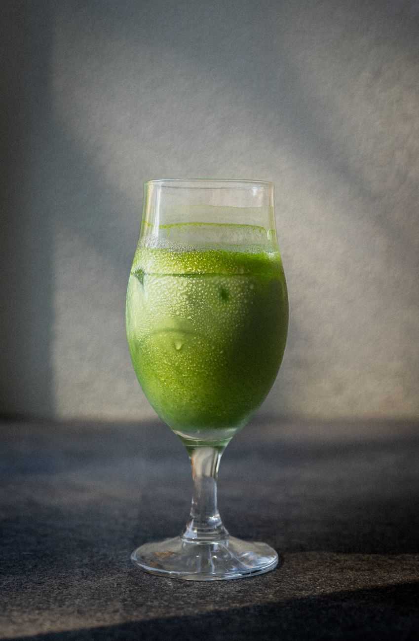 Vibrant green matcha powder in a ceramic bowl showing fine texture with bamboo whisk resting beside it.