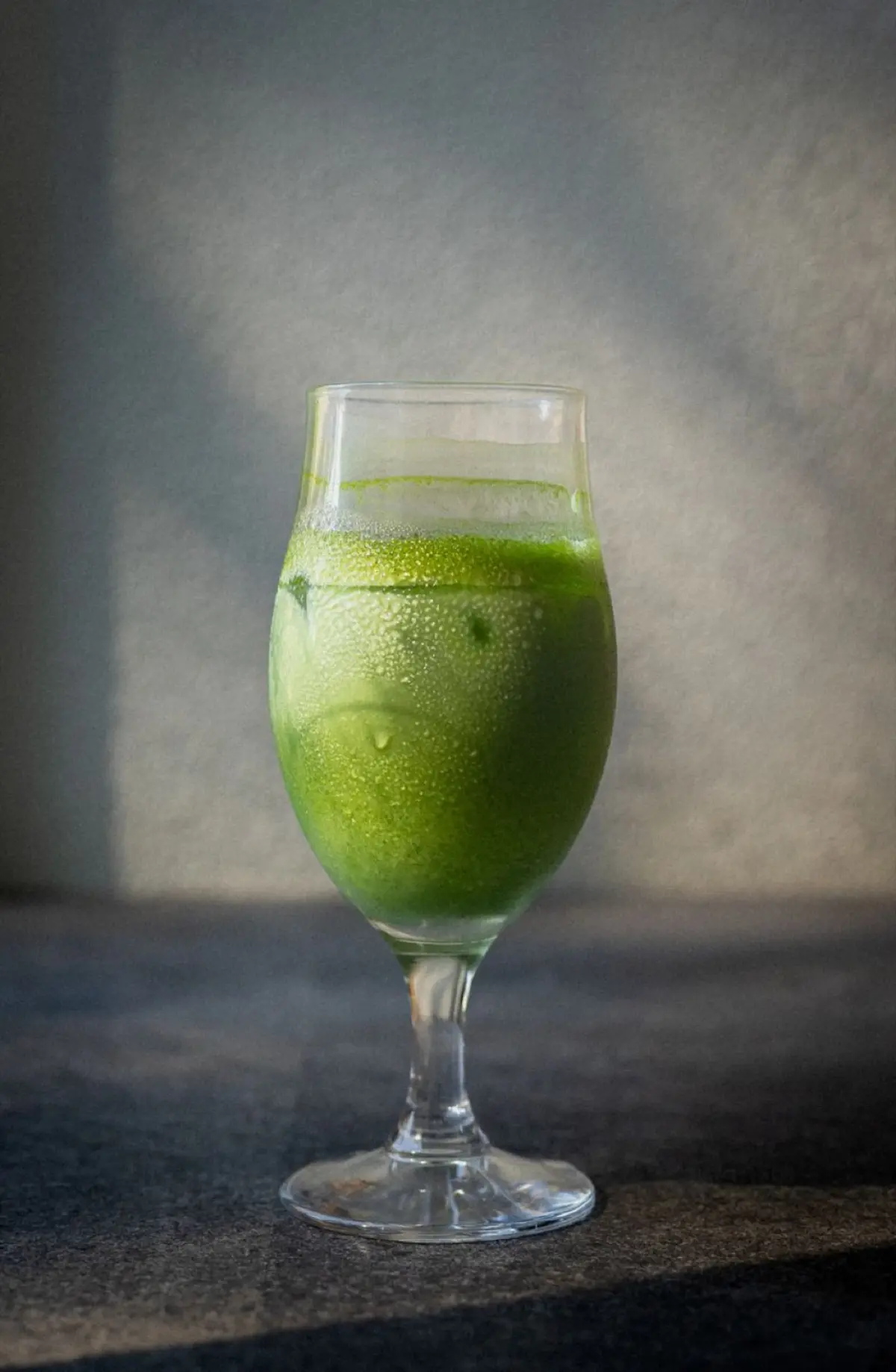 Vibrant green matcha powder in a ceramic bowl showing fine texture with bamboo whisk resting beside it.