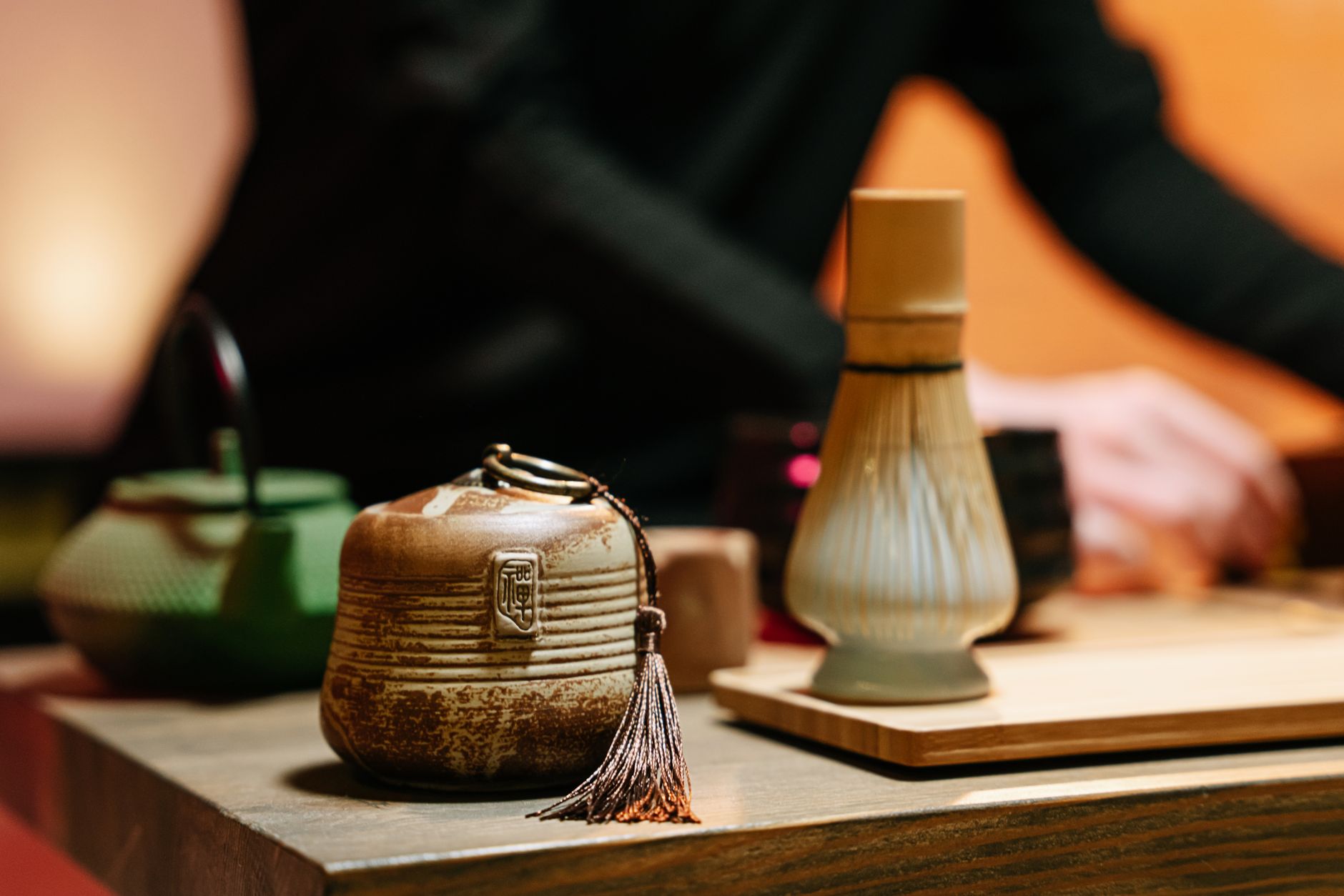 Traditional stone mill grinding vibrant green matcha powder in a Japanese tea ceremony room with bamboo utensils nearby.