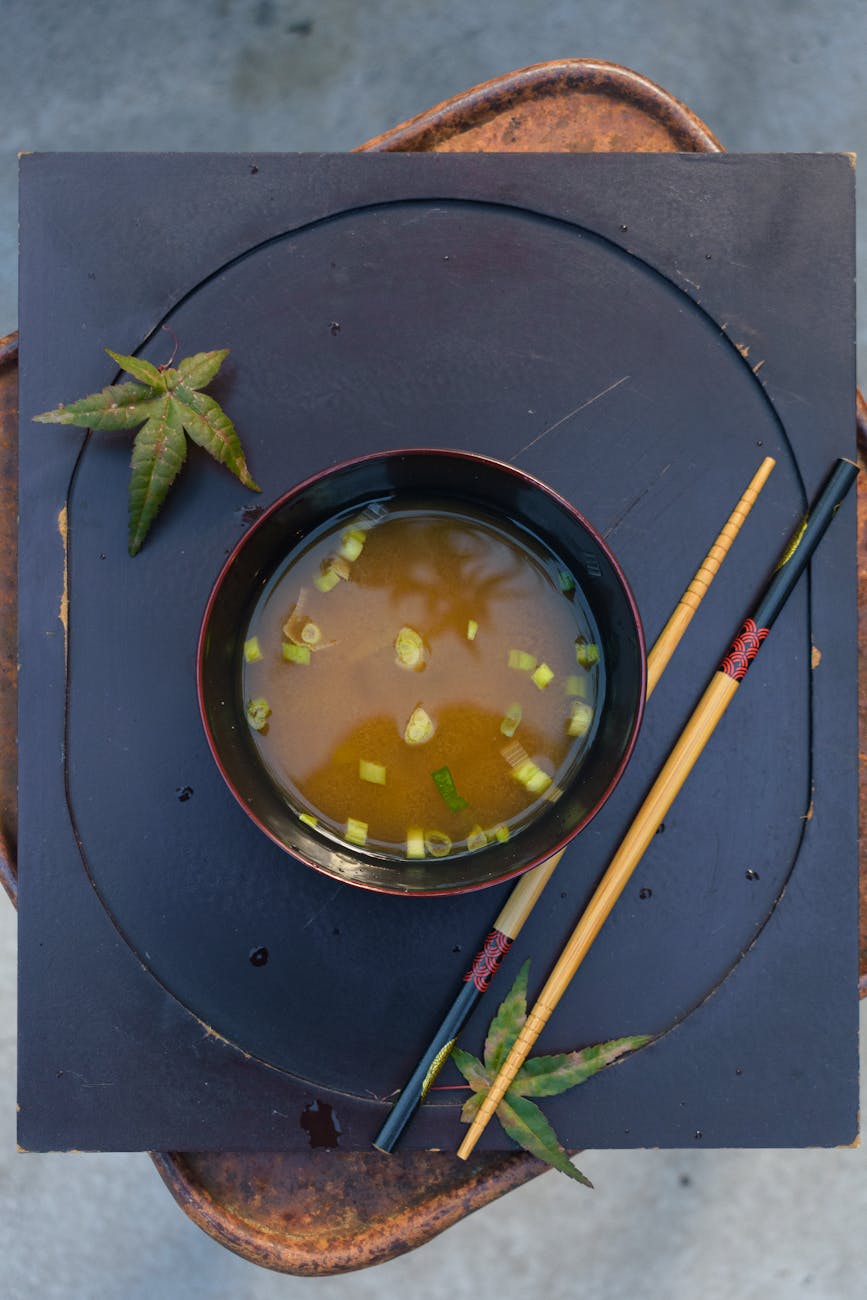 Traditional wooden barrel filled with dark brown miso paste, showing its smooth texture with a wooden paddle resting inside.