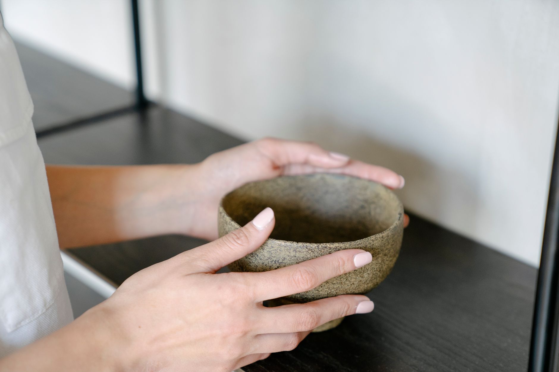 Traditional Japanese chawan tea bowl with frothy green matcha, bamboo whisk resting beside it on wooden surface.