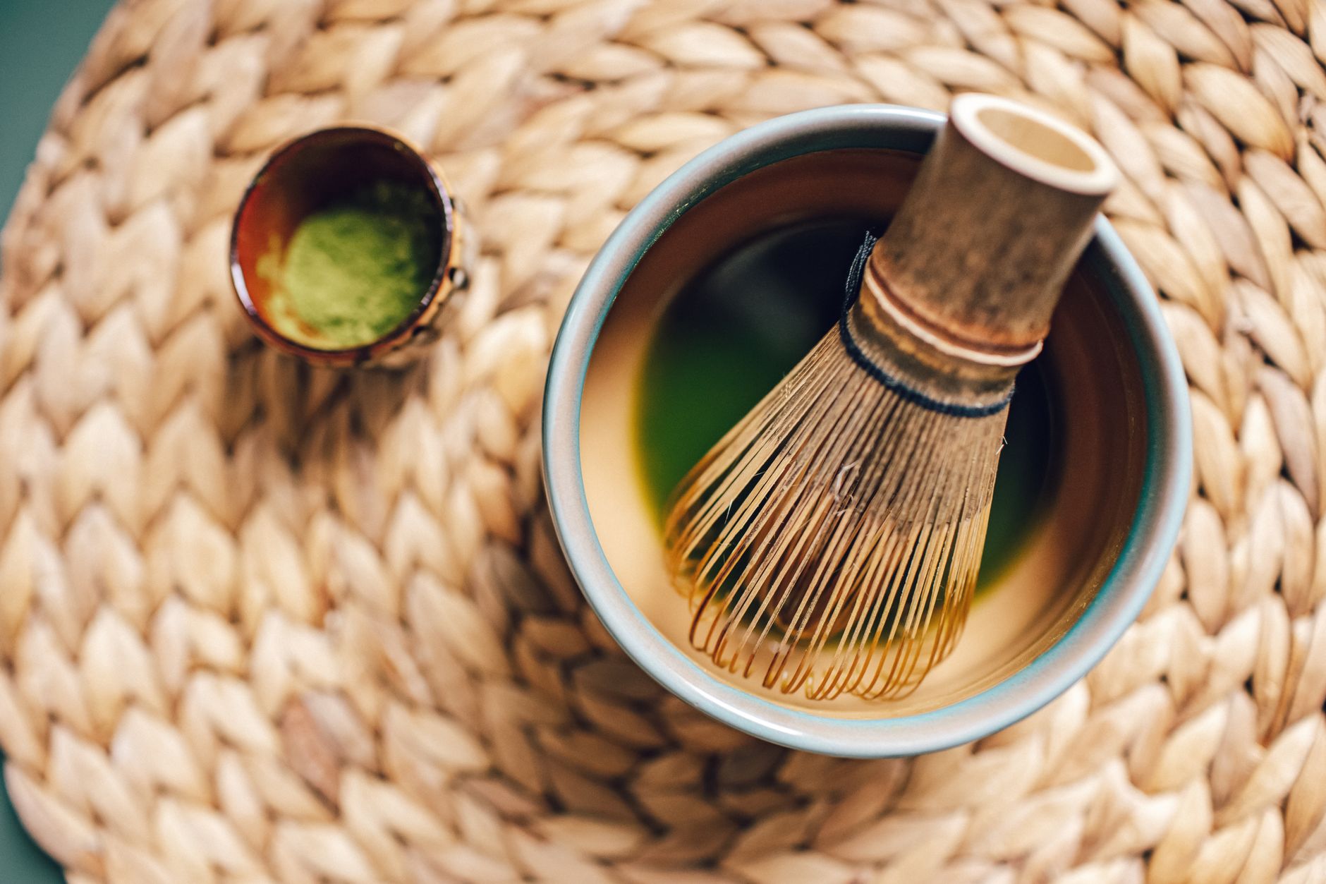 Craftsman's hands carefully shaping a slender bamboo tea scoop over gentle heat to create the traditional curved form.
