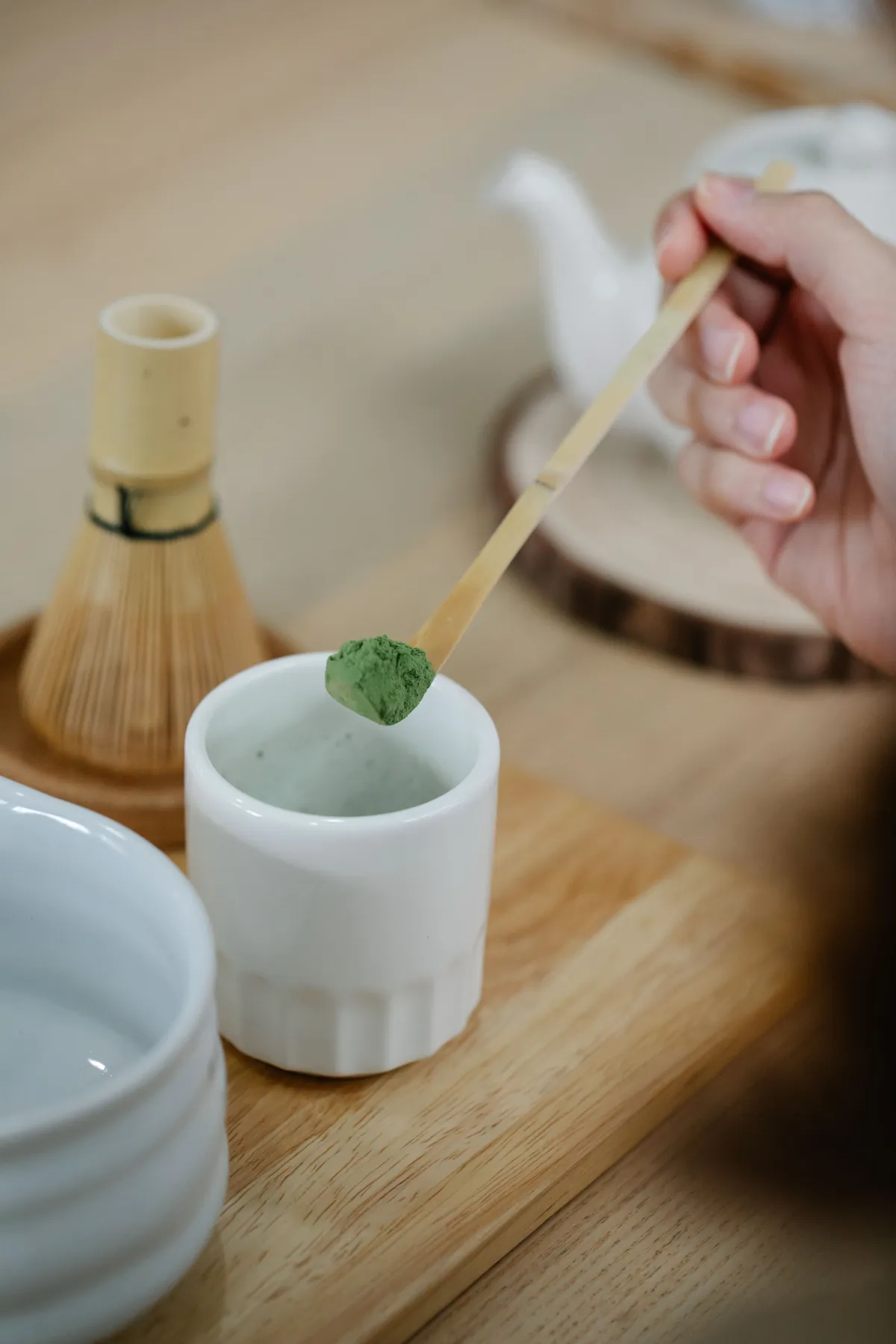 Craftsman's hands carefully shaping a slender bamboo tea scoop over gentle heat to create the traditional curved form.