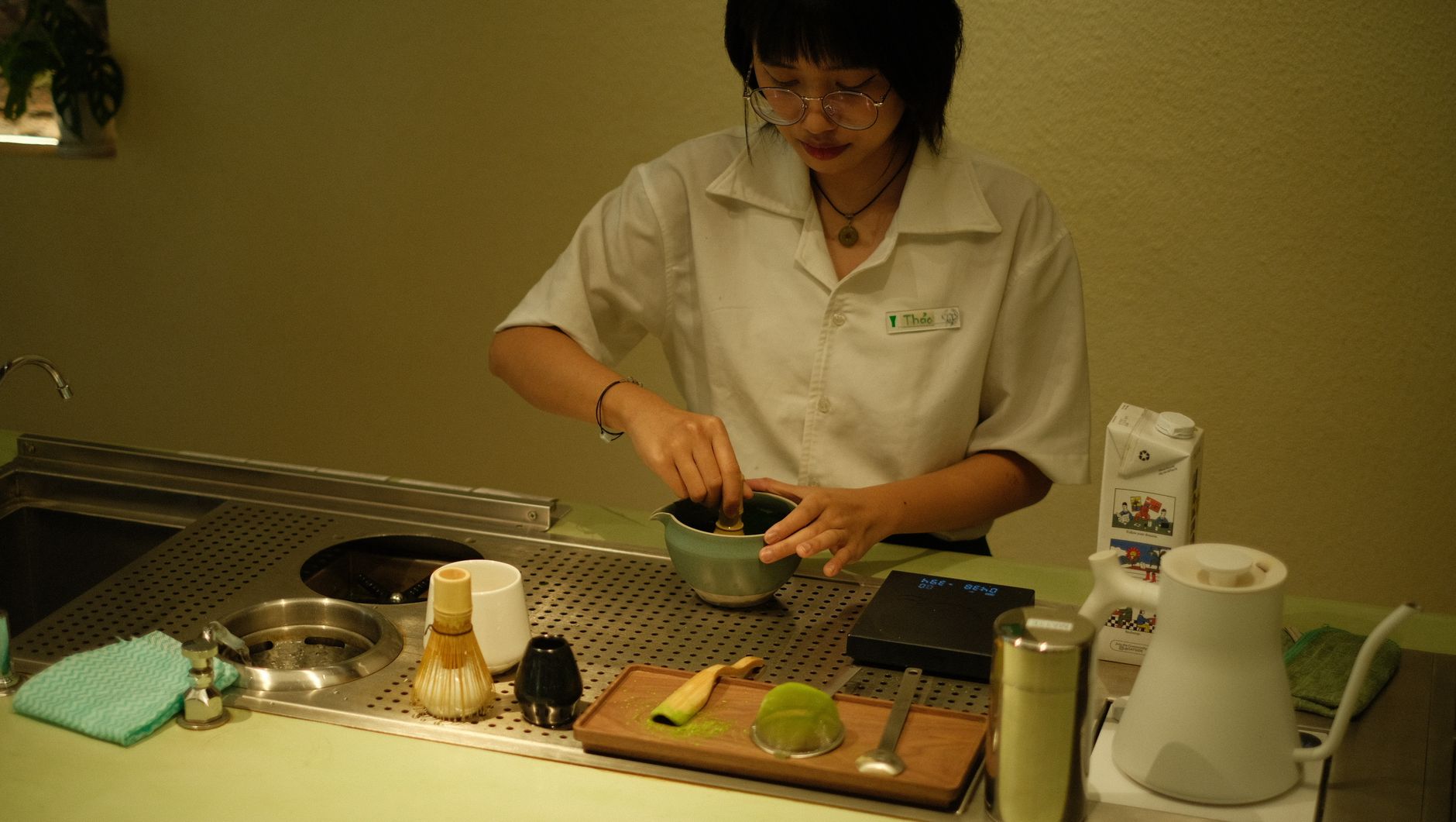 Thick koicha matcha in a ceramic tea bowl showing dense, paste-like consistency with bamboo whisk resting beside it.
