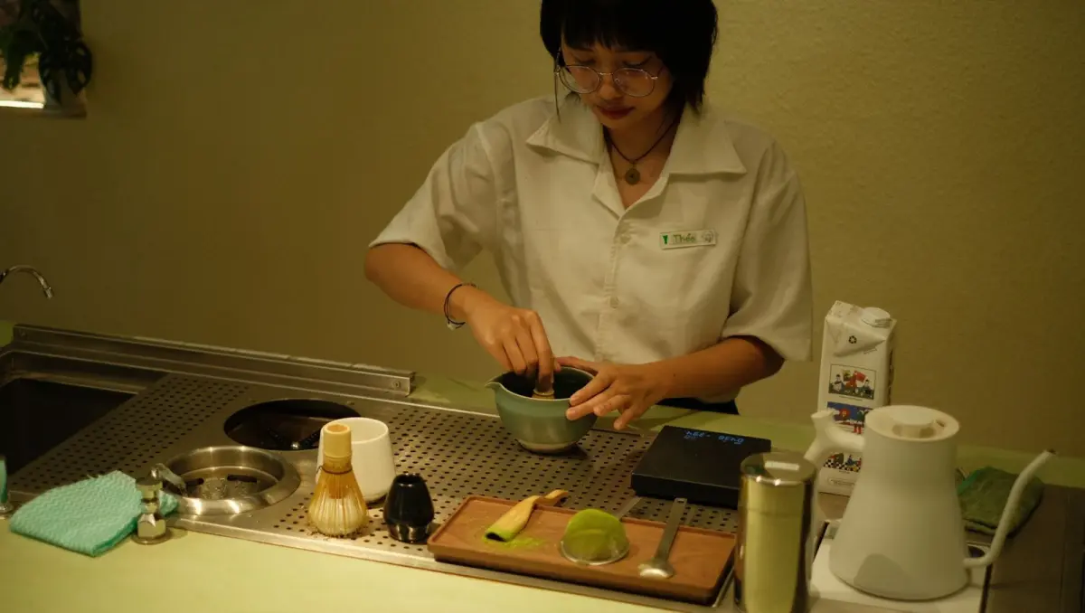 Thick koicha matcha in a ceramic tea bowl showing dense, paste-like consistency with bamboo whisk resting beside it.