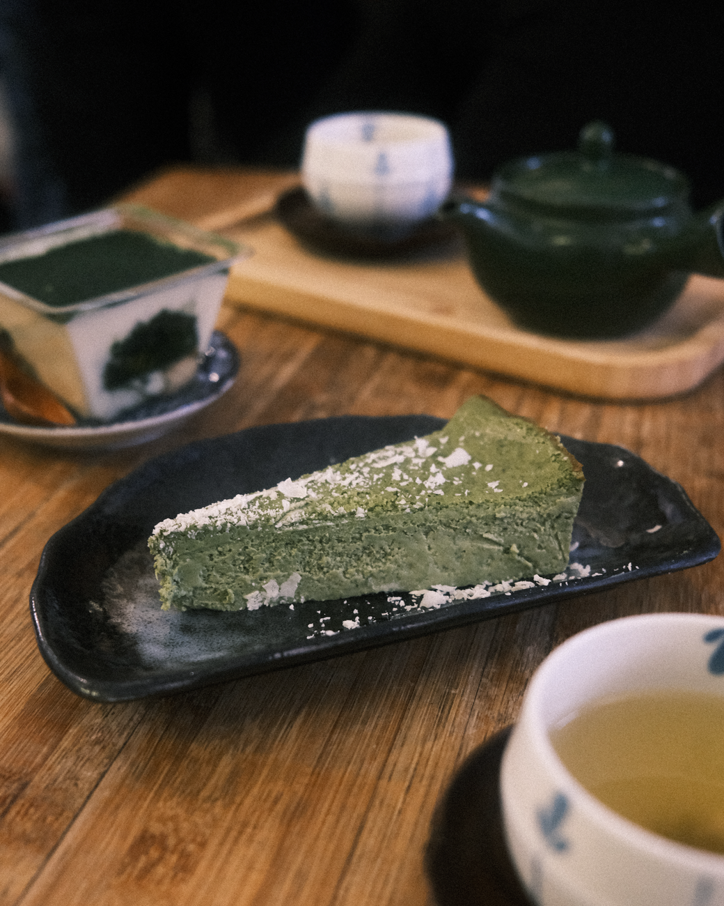 A bamboo whisk whisking thin, bright green usucha matcha in a ceramic tea bowl, creating a frothy layer on the surface.