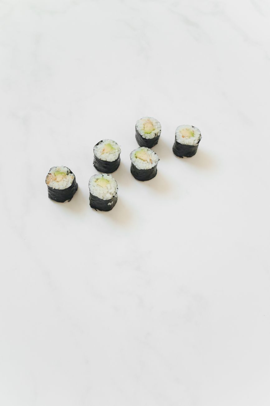 Glossy white sushi rice seasoned with rice vinegar, shaped into small oval mounds on a wooden cutting board.