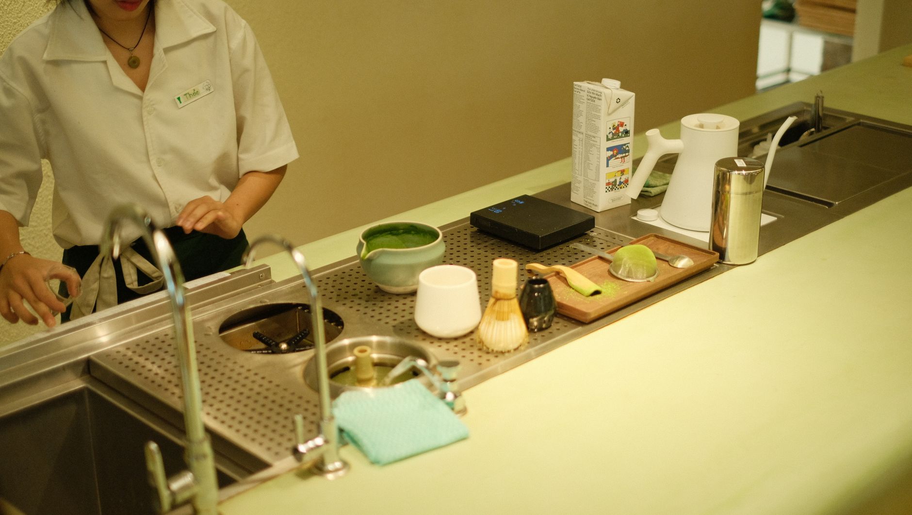 Stone mill grinding vibrant green tencha leaves into fine matcha powder, showing the traditional Japanese tea production process.
