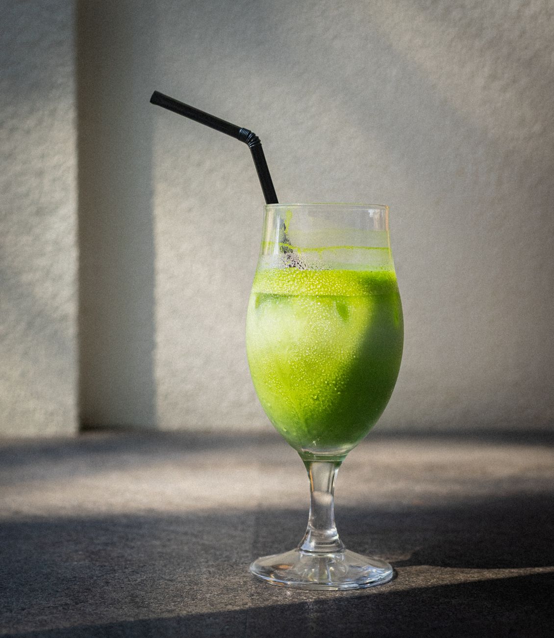 Stone mill grinding vibrant green tencha leaves into fine matcha powder, showing the traditional Japanese tea production process.