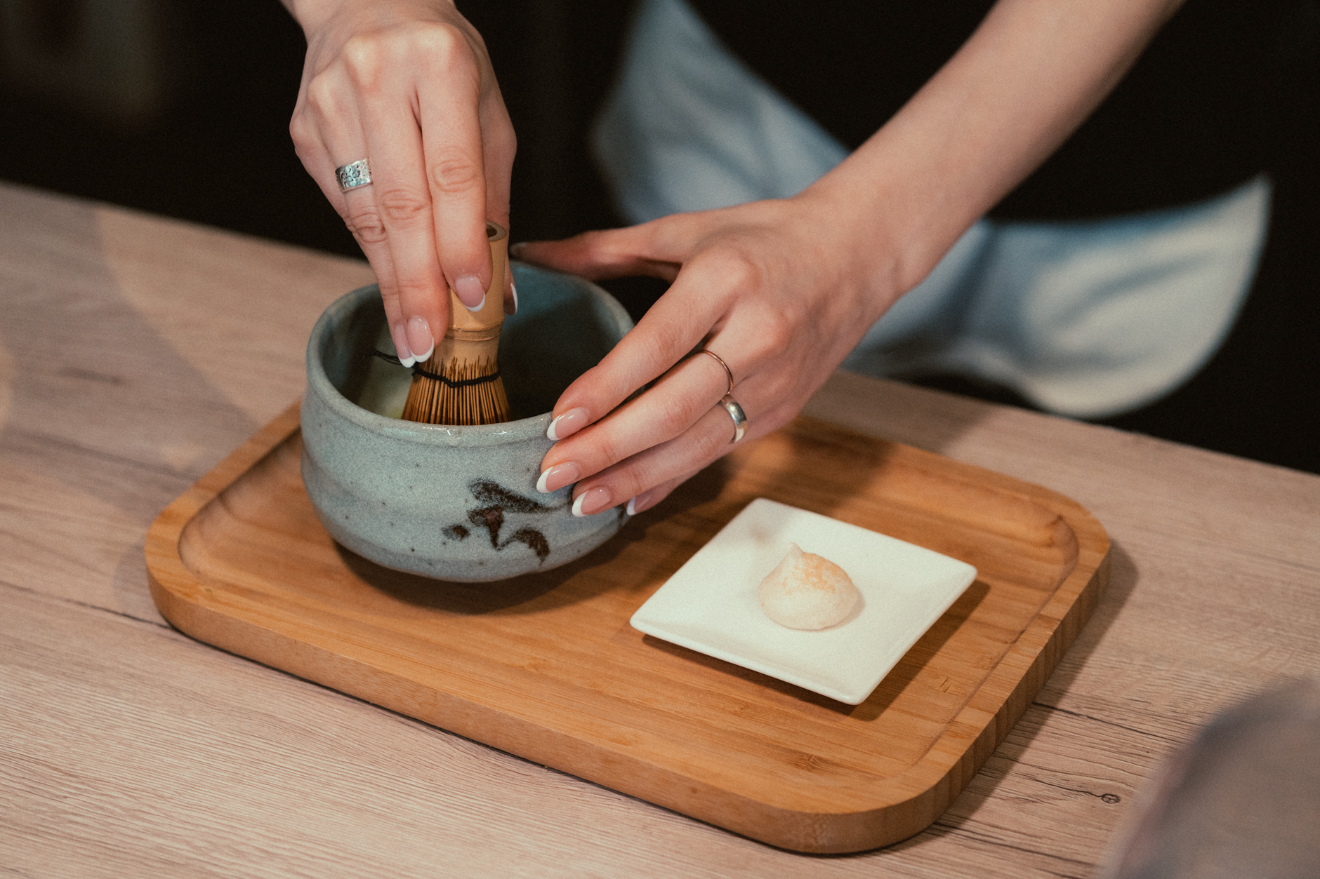 Traditional granite matcha stone mill with grooved surface slowly grinding bright green tea leaves into fine powder in Japanese workshop.