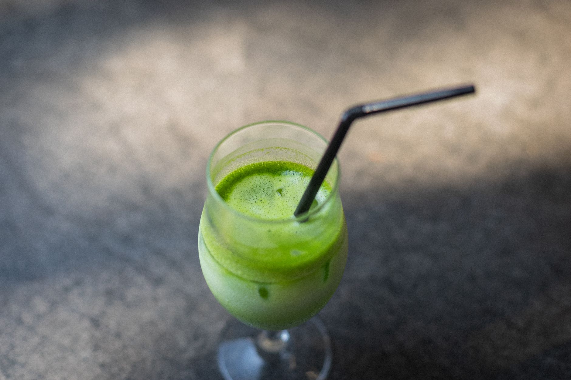 Sealed matcha tin with bamboo scoop resting beside it on a dark wooden surface in soft natural light.
