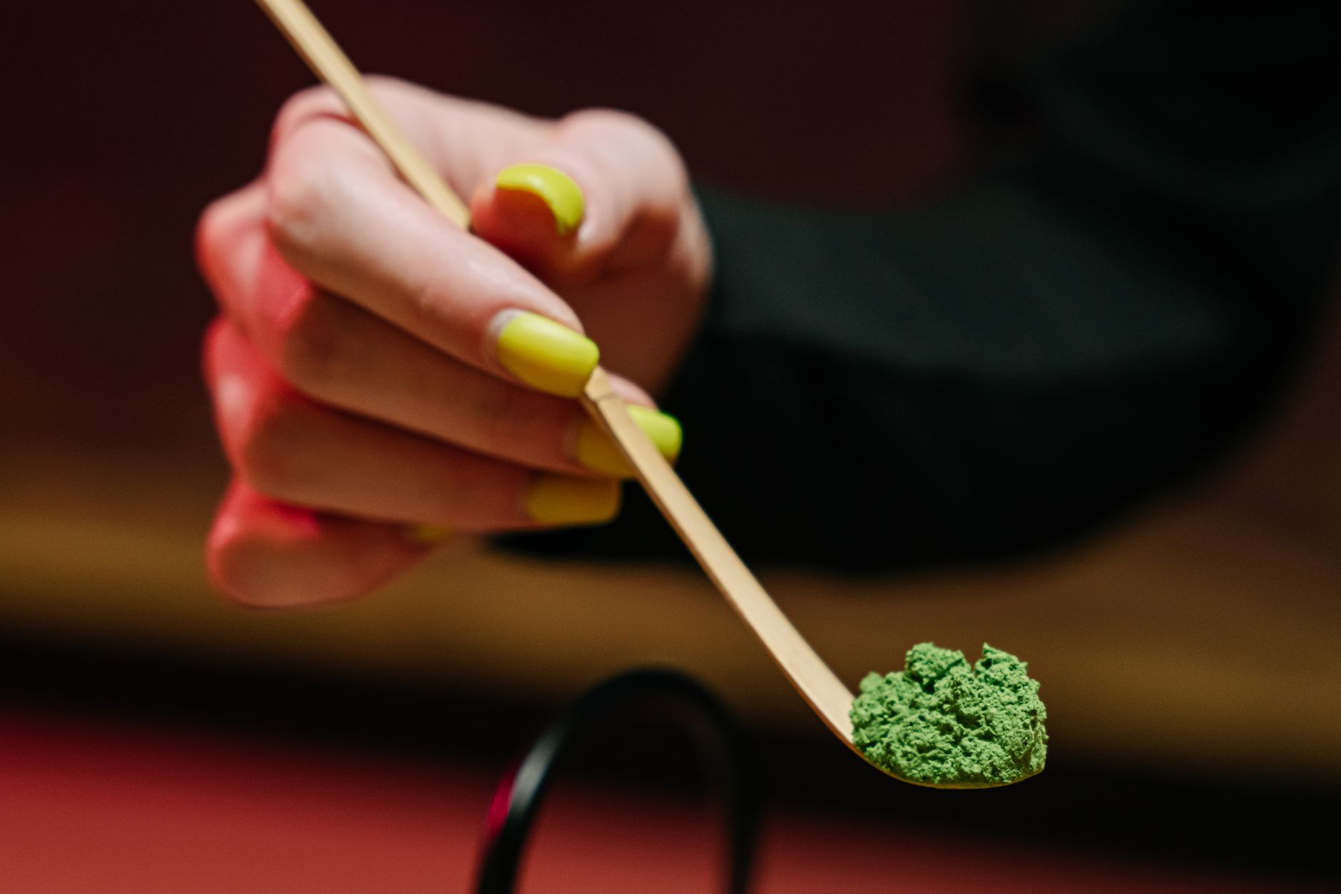 Thick, creamy matcha foam with fine bubbles sits atop bright green tea in a traditional ceramic bowl.