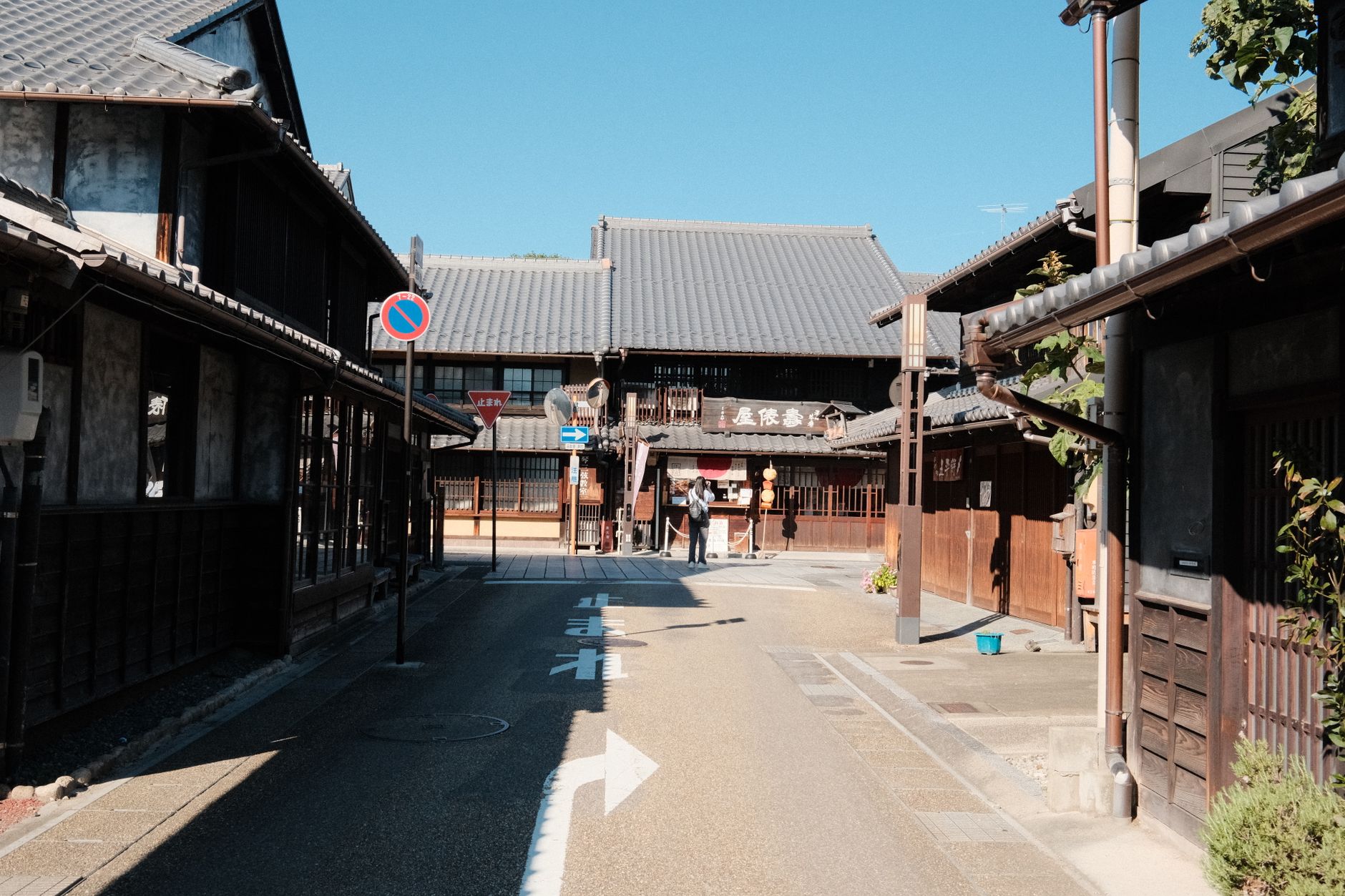 Edo-period travelers walking along the tree-lined Tokaido Road with Mount Fuji visible in the distance under clear skies.