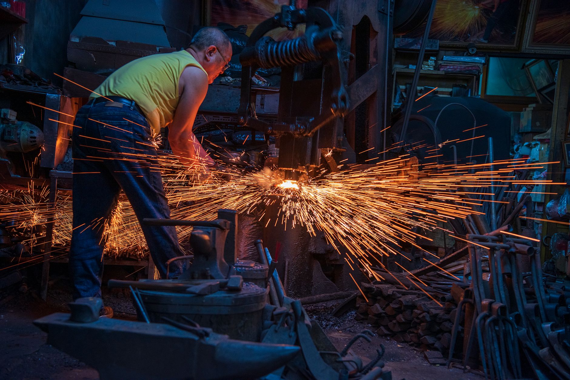 Swordsmith hammering glowing steel on an anvil in a traditional Japanese forge with sparks flying.