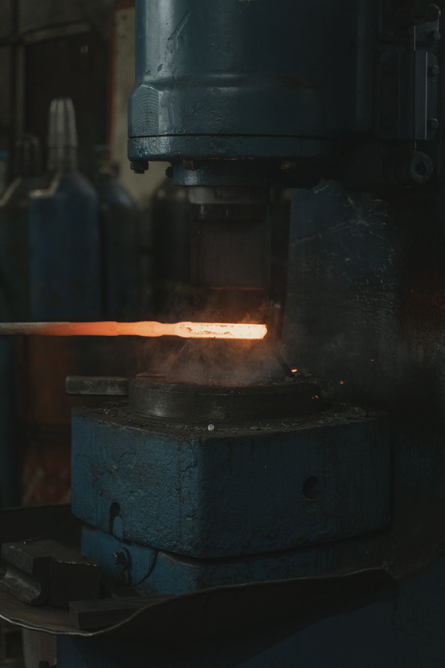 Traditional Japanese tatara furnace with craftsmen loading iron sand and charcoal to produce tamahagane steel for sword making.