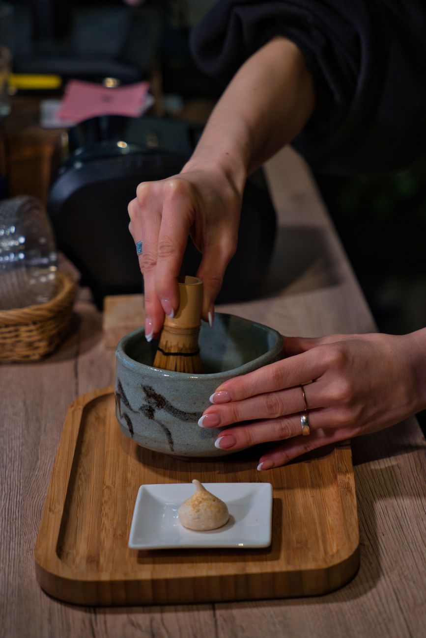 Craftsman's hands splitting a single bamboo node into fine tines using a small knife on a wooden workbench.