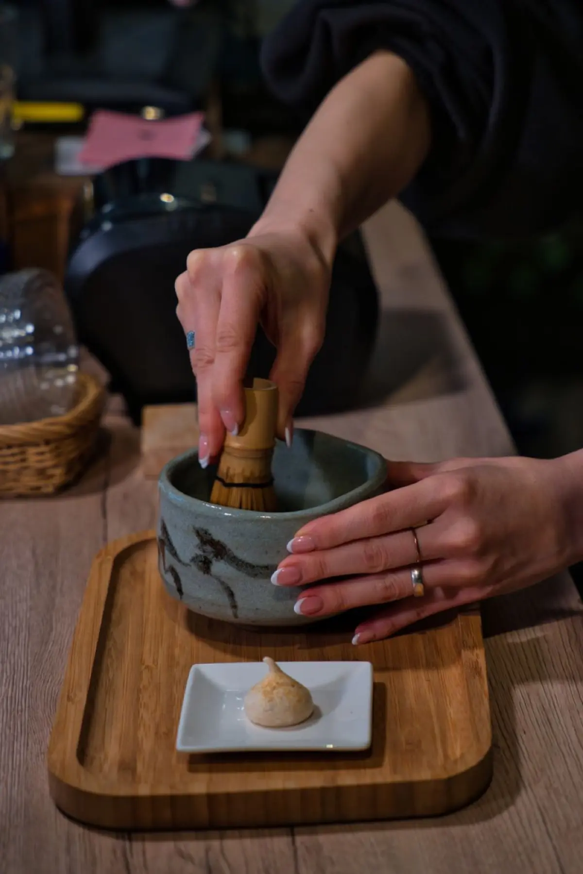 Craftsman's hands splitting a single bamboo node into fine tines using a small knife on a wooden workbench.