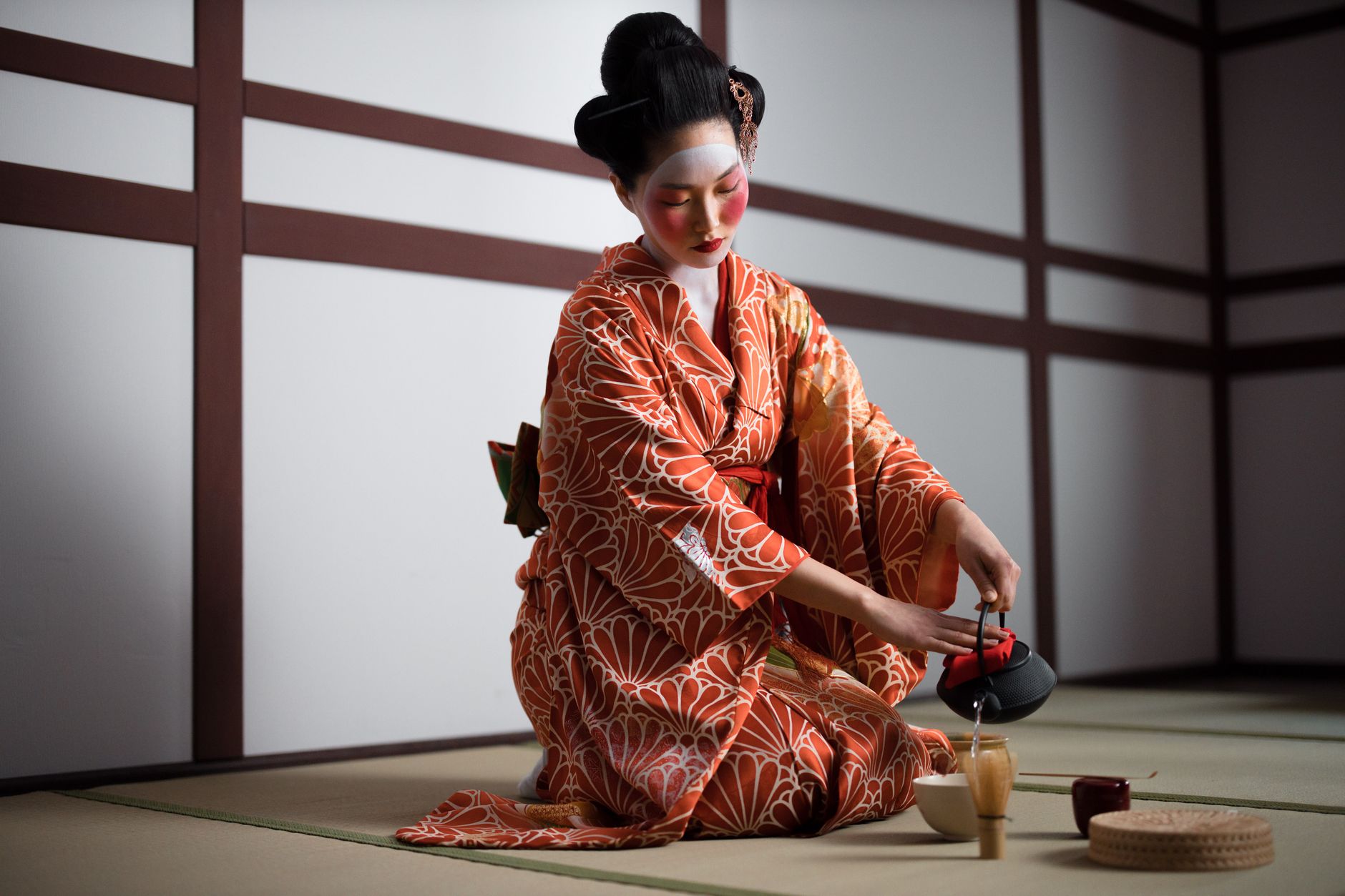 Traditional Japanese tea room with tatami mats, sliding shoji screens, and a simple tokonoma alcove displaying minimalist flower arrangement.