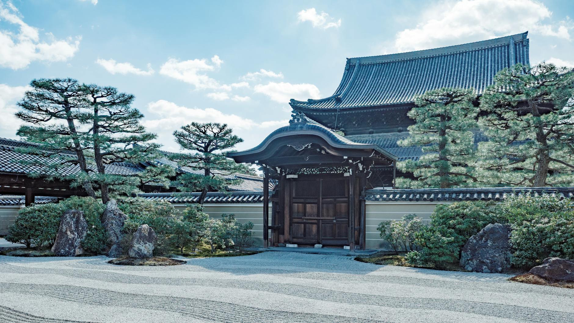 Carefully raked white gravel creates rippling wave patterns around moss-covered rocks in a traditional Japanese temple garden.