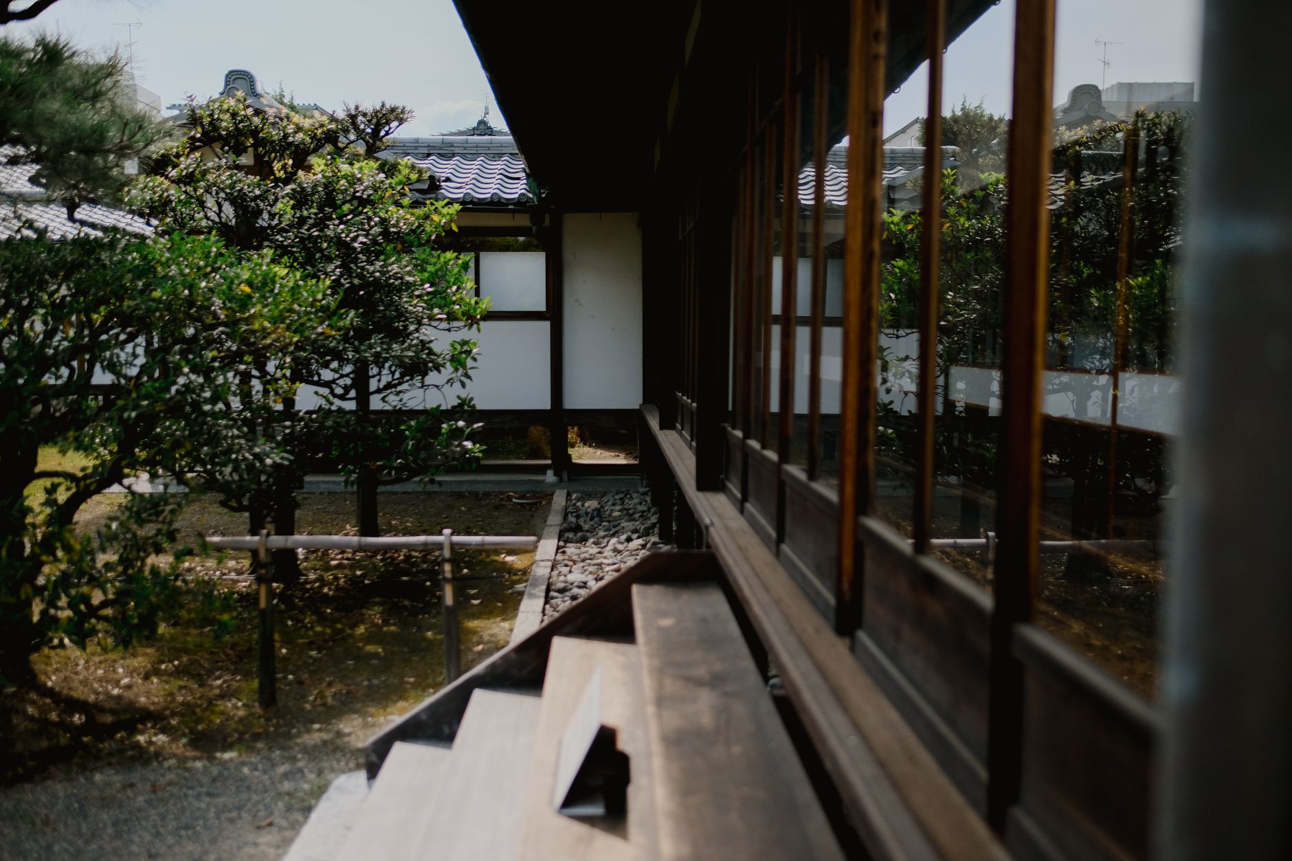 Raked white gravel patterns flow around weathered stones and moss in a traditional Japanese Zen temple dry garden.