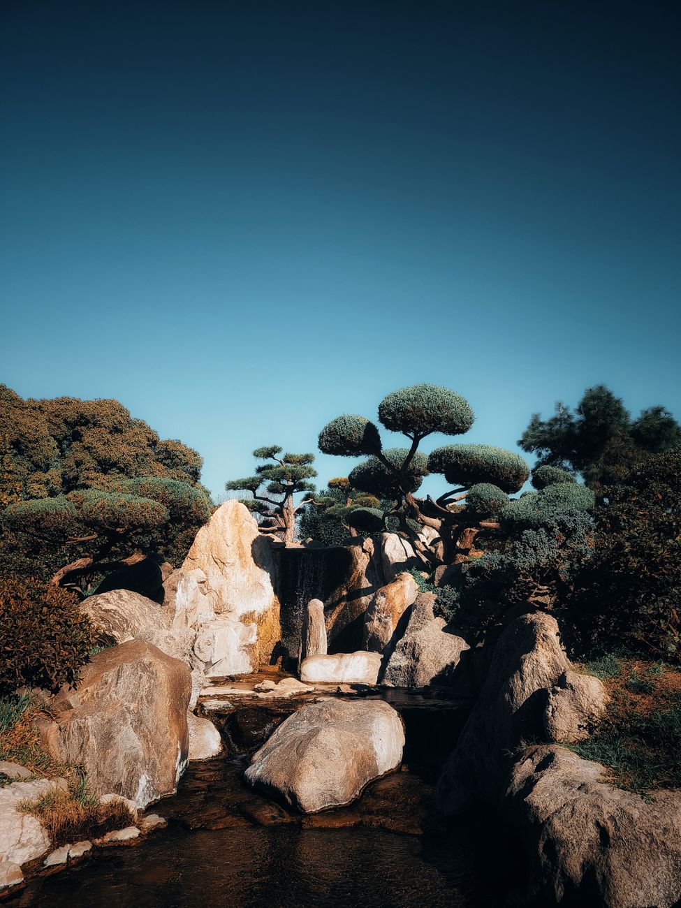 Raked white gravel patterns flow around weathered stones and moss in a traditional Japanese Zen temple dry garden.