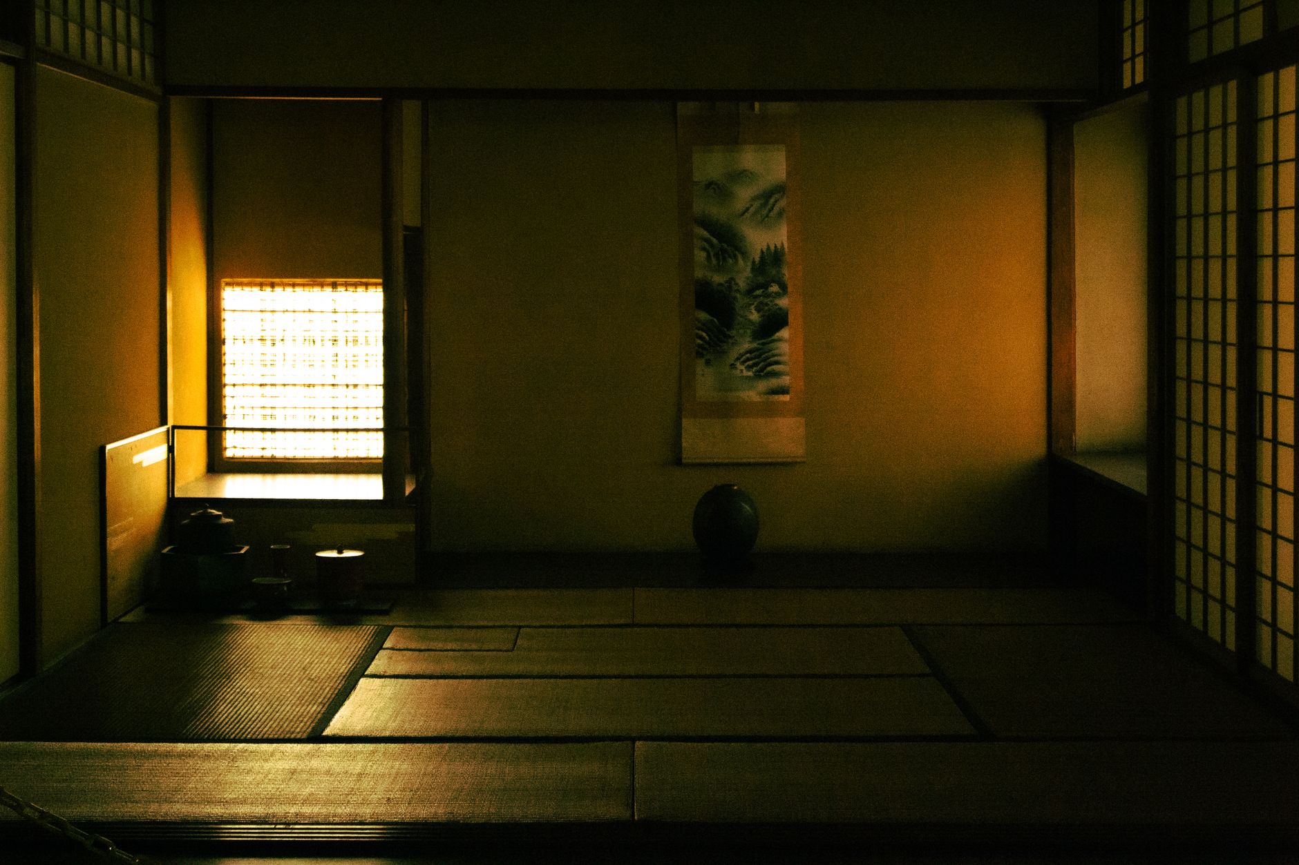 Simple Japanese tea room with tatami mats, shoji screens, and single flower arrangement demonstrating zen principles in spatial design.
